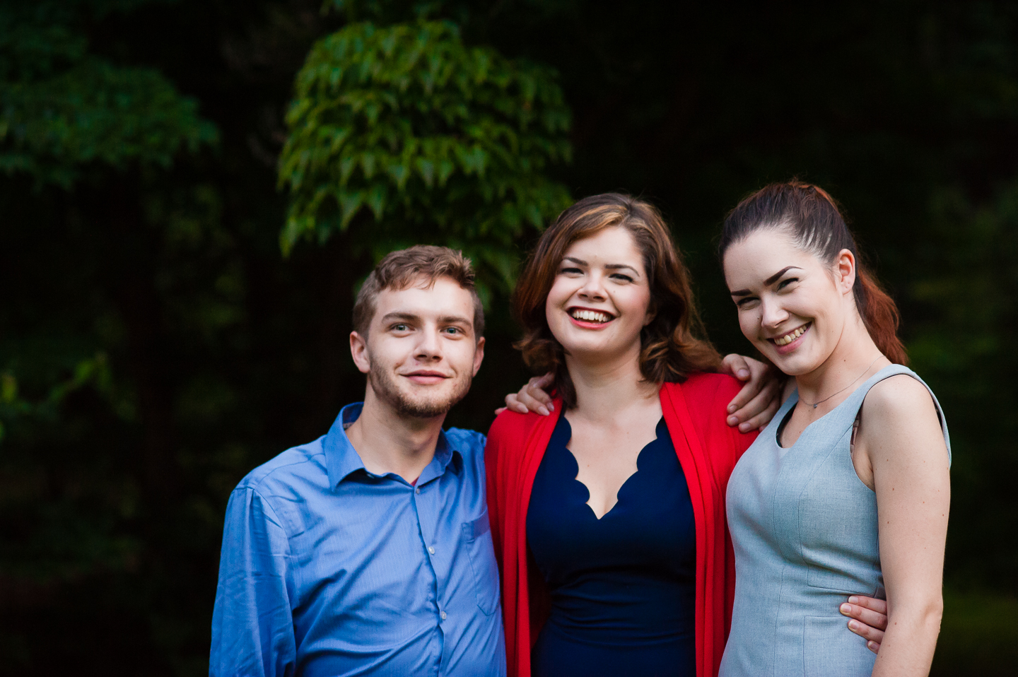 bride and her two siblings smile for a quick family picture