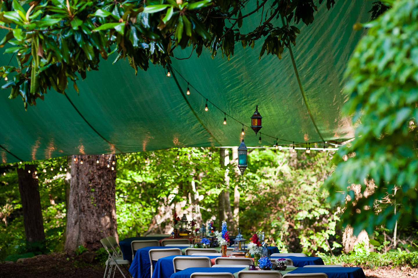 beautiful flowers adorned the bright blue table clothes which sat underneath hand strewn lanterns 