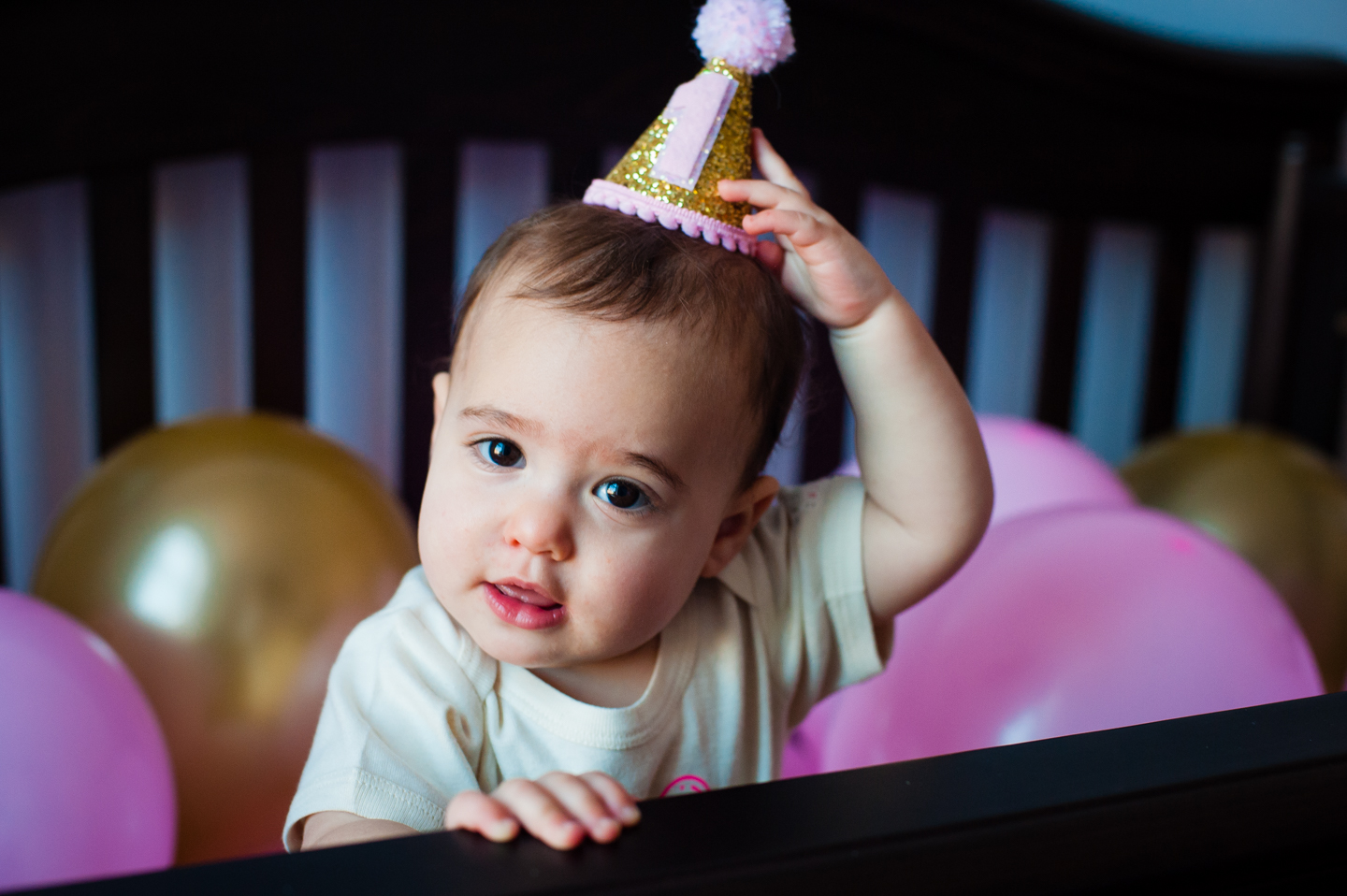 Cute 1 year old girl trying to pull her crown off her head