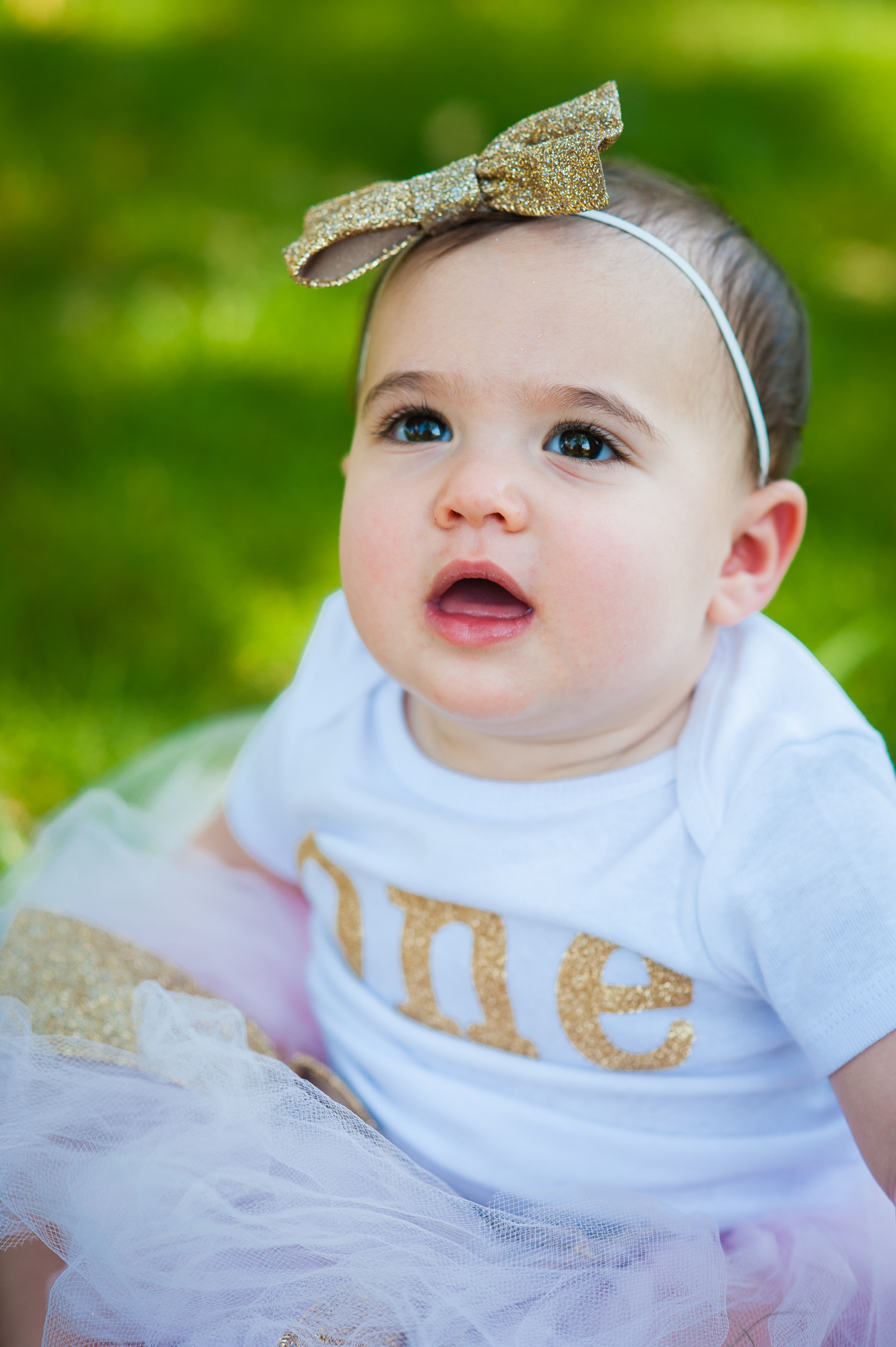 adorable baby girl sitting in the grass during her outdoor birthday portraits