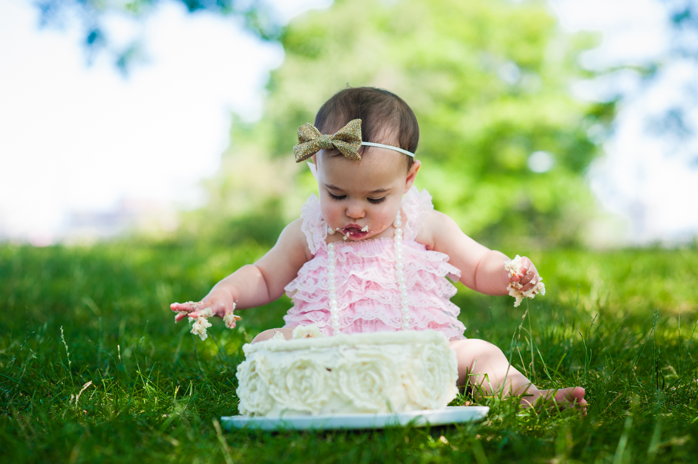 baby during her 1st year cake smash looks at her cake 
