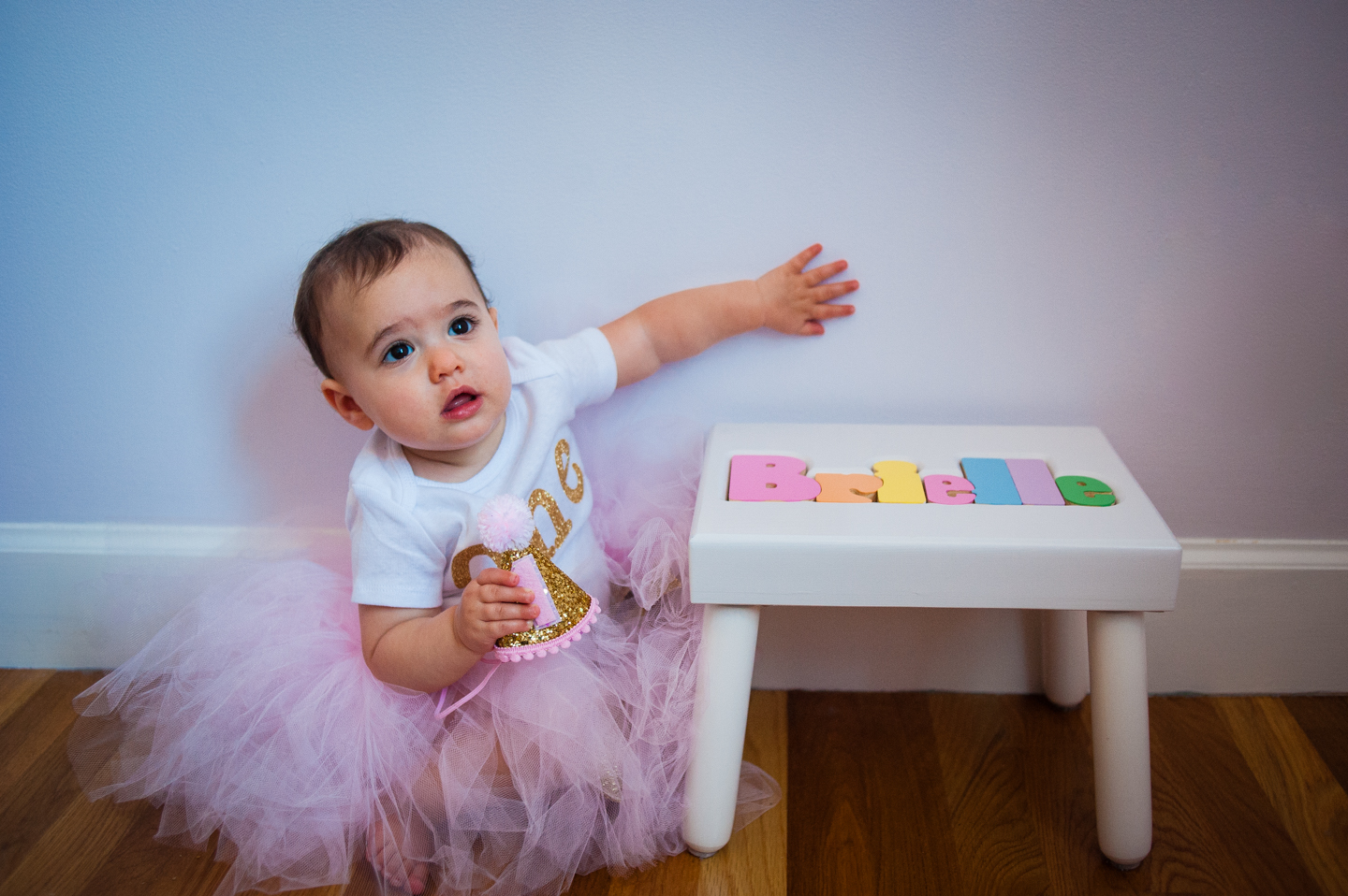 cute baby poses next to a stool with her name on it