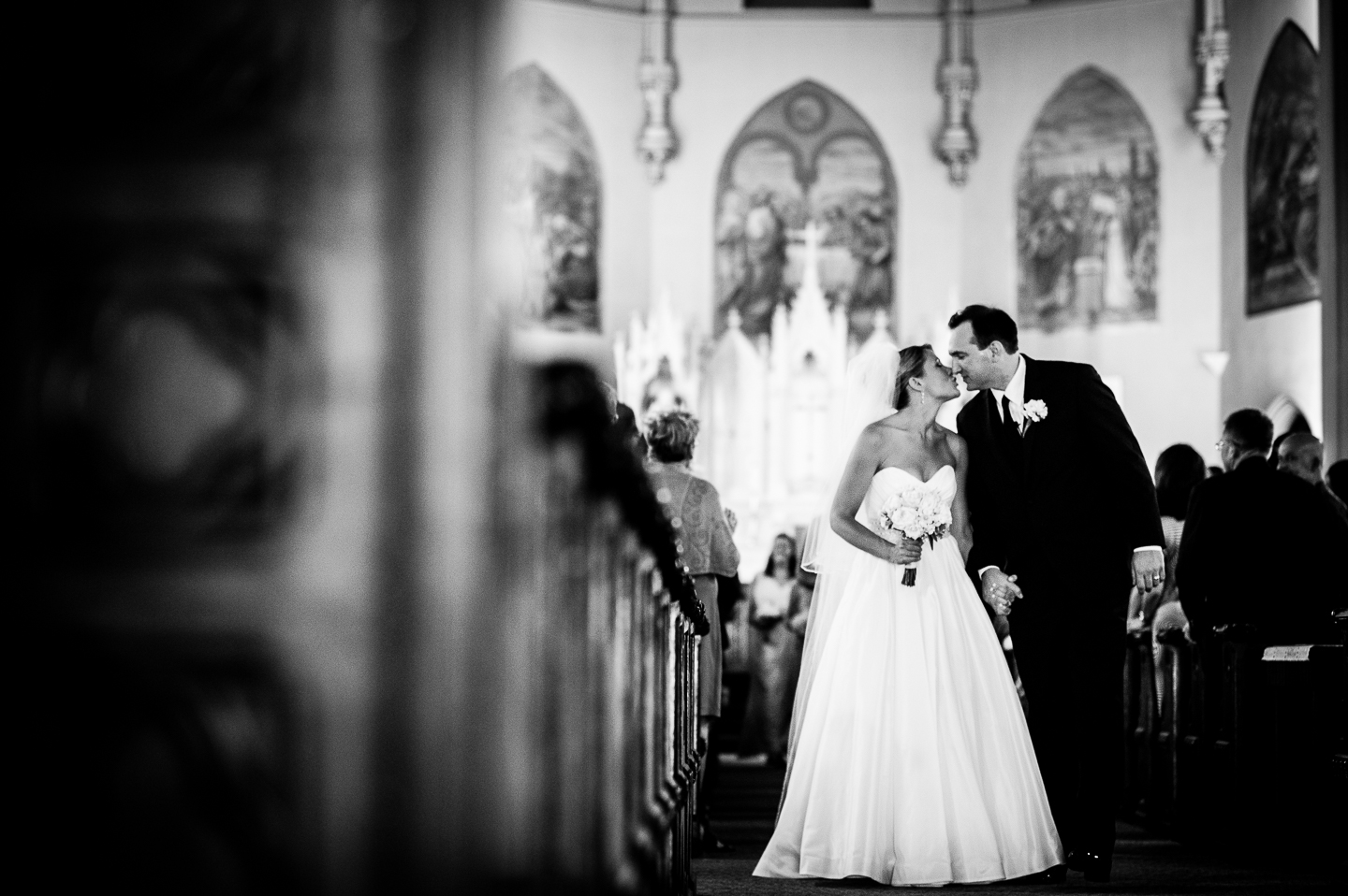 Newly married couple gives each other a kiss during their walk up the aisle as husband and wife 