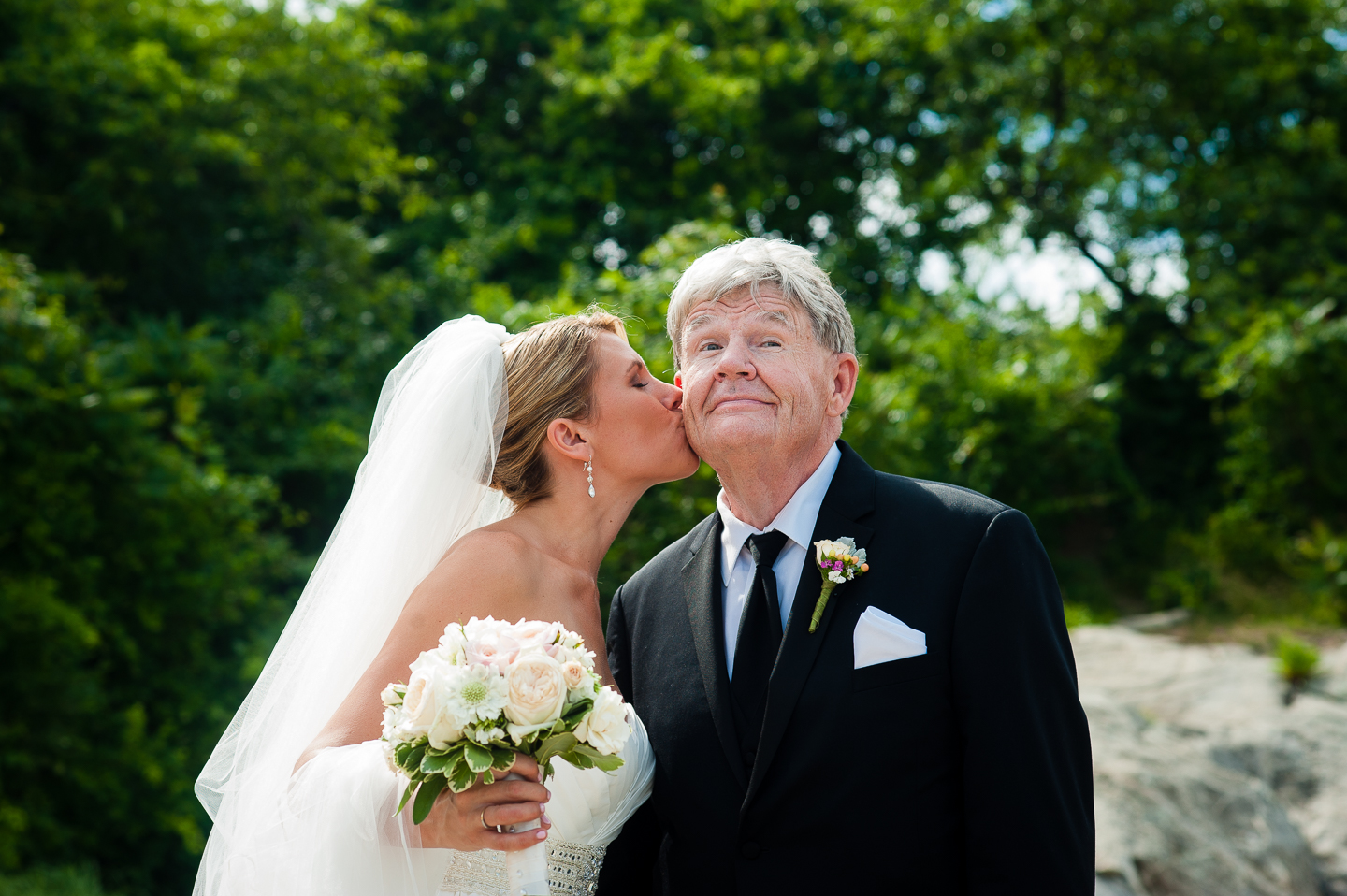 a stunning bride gives her dad a sweet kiss on the cheek during family pictures