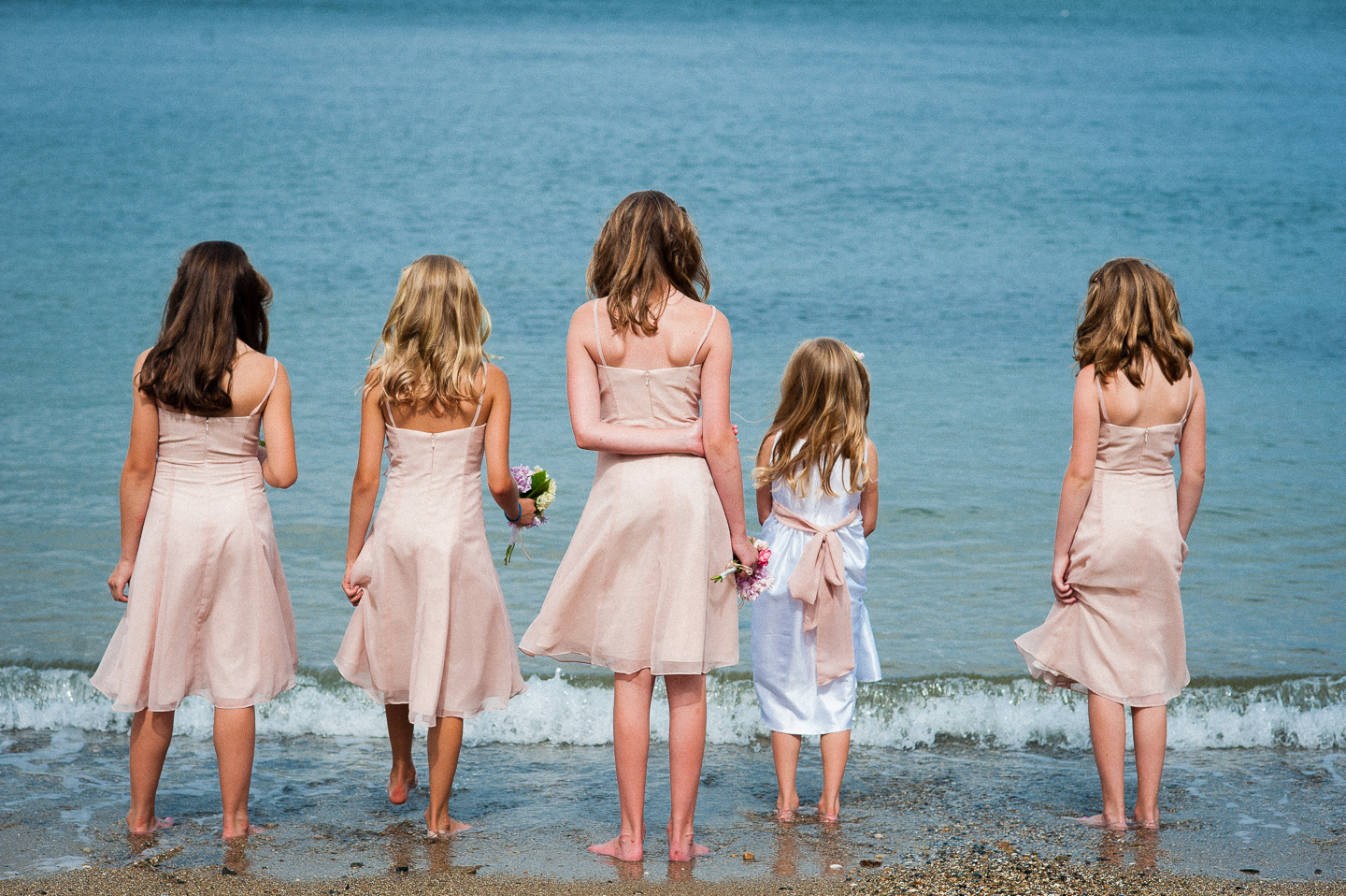 the jr bridesmaids seeing how close they can get to the ocean without getting their dresses wet