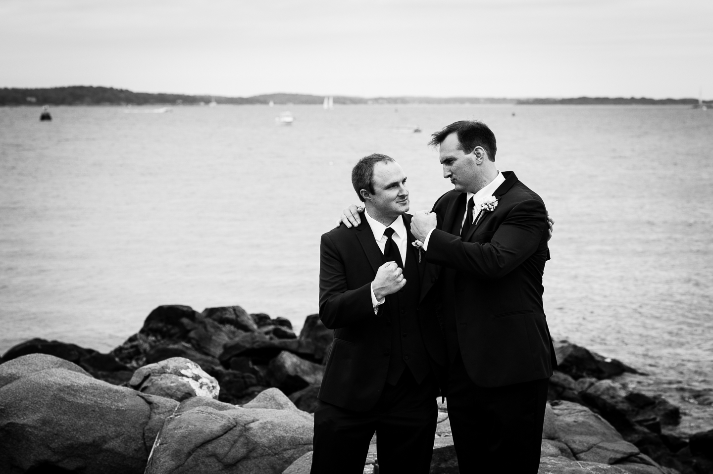 the handsome groom and his brother pose on some rocks by the ocean for a quick picture 