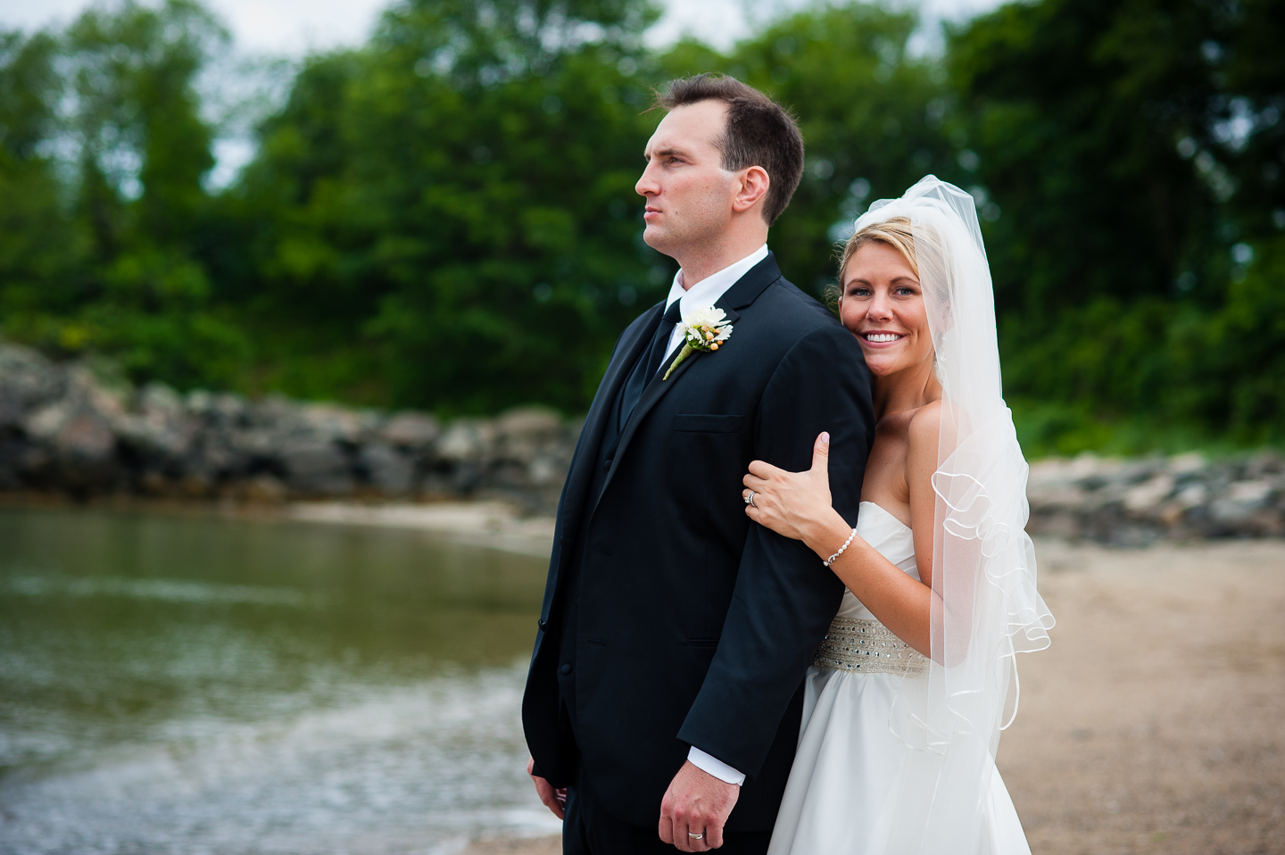 a gorgeous bride rests her cheek on her husbands shoulder during seaside couples portraits