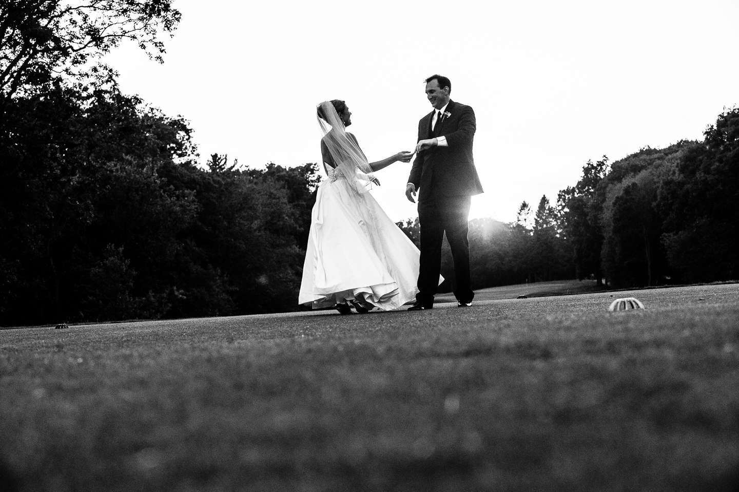 a bride and groom practice their first dance in a field 