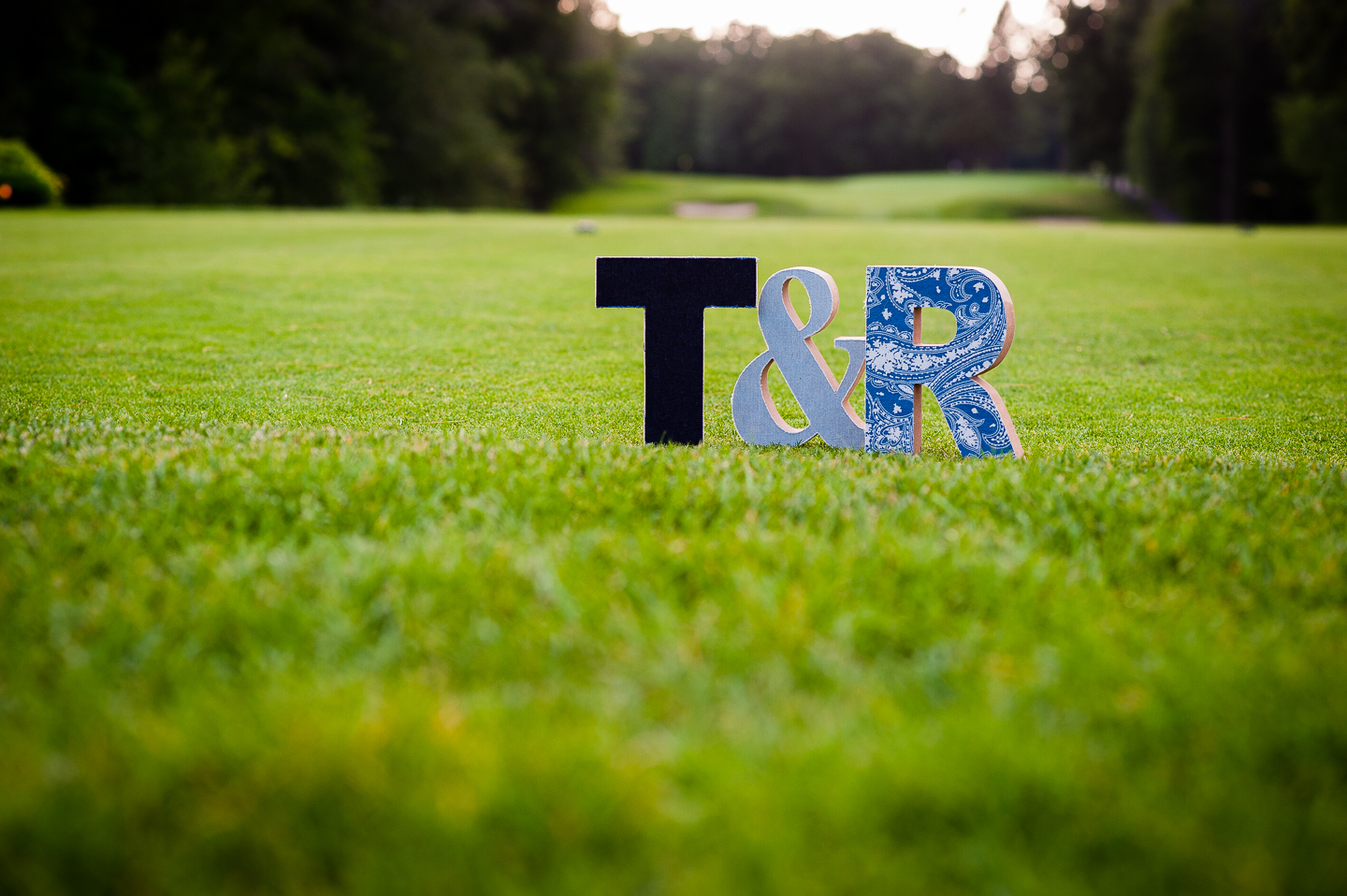 wooden letters cut in the shape of brides and grooms initials are placed on the golf course 