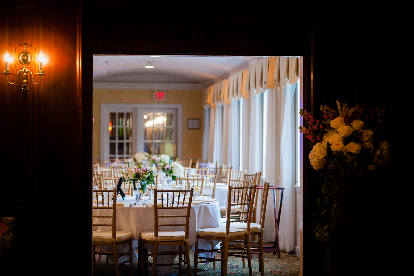 a gorgeous ballroom is decorated by pretty white and pink flowers for this wedding reception  