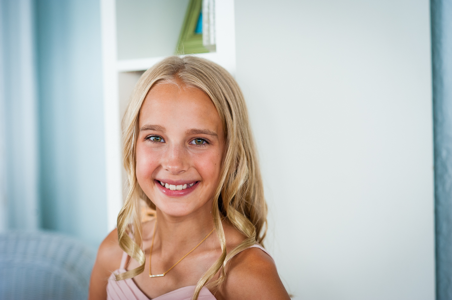 Adorable Jr Bridesmaid smiles at the camera during getting ready