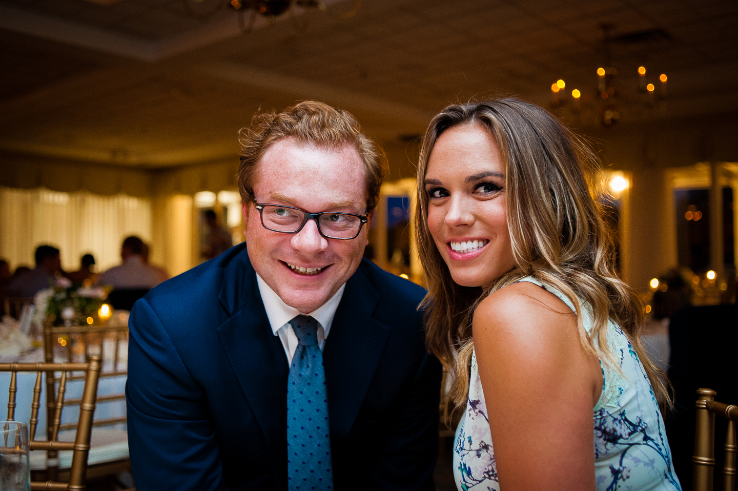 two wedding guests watching friends goof off on the dance floor  