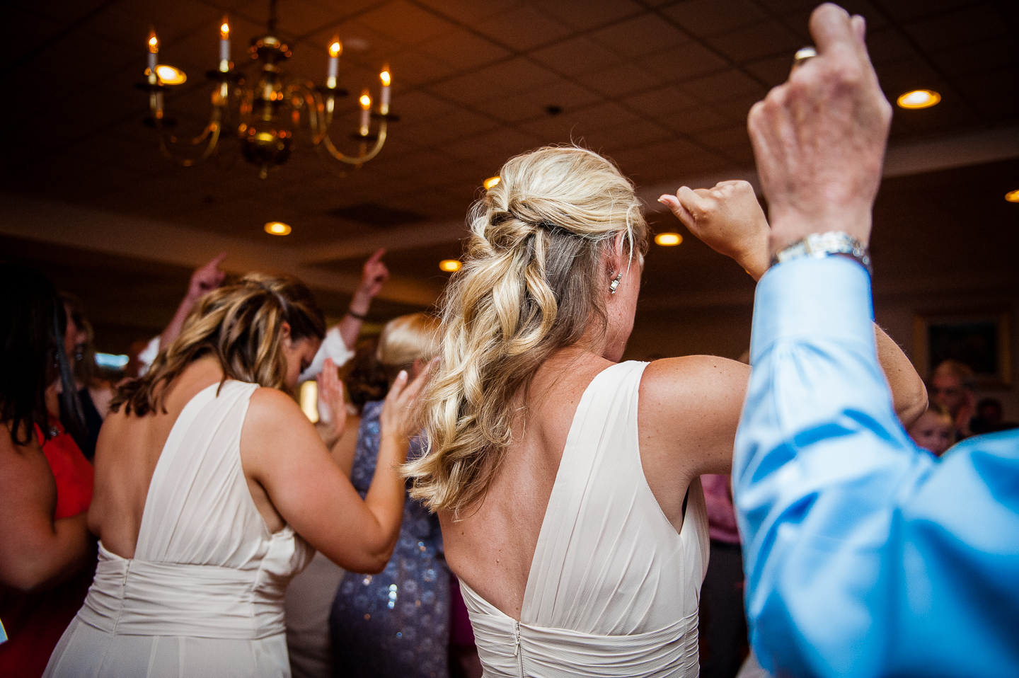 bridemaid surrounded by guests throw their hands in the air 