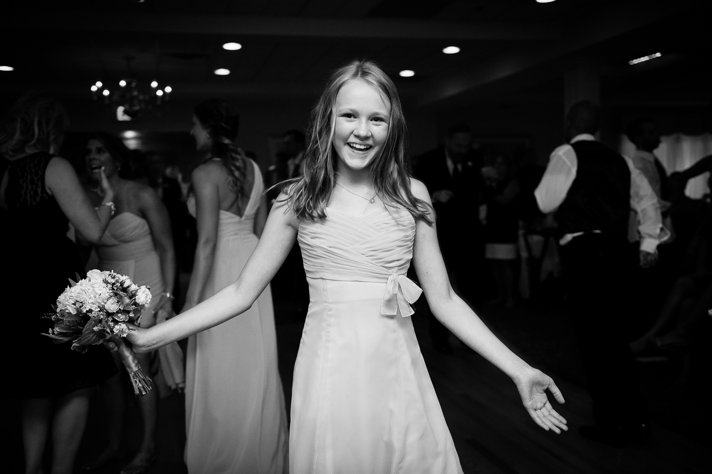 a jr bridesmaid holds the bouquet after catching it 