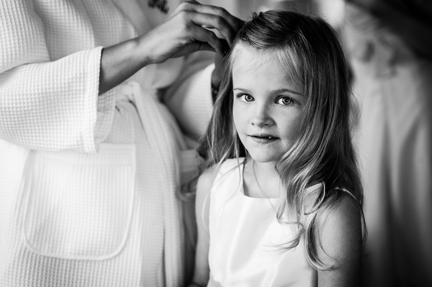 cutest flower girl smiles as bride does her hair