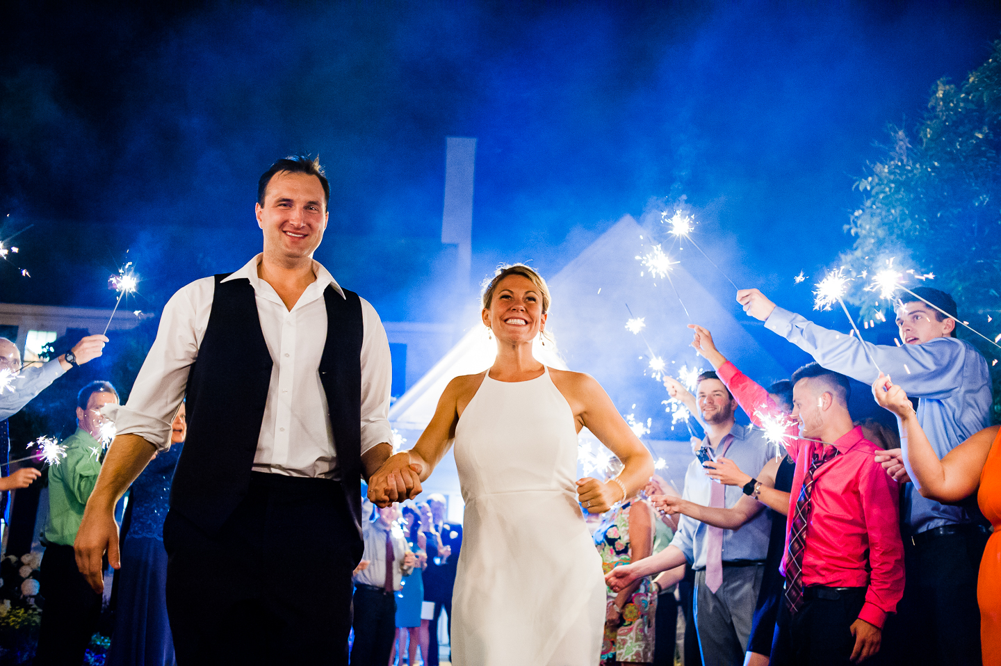 bride and groom happily run down the aisle of sparklers during their send off 