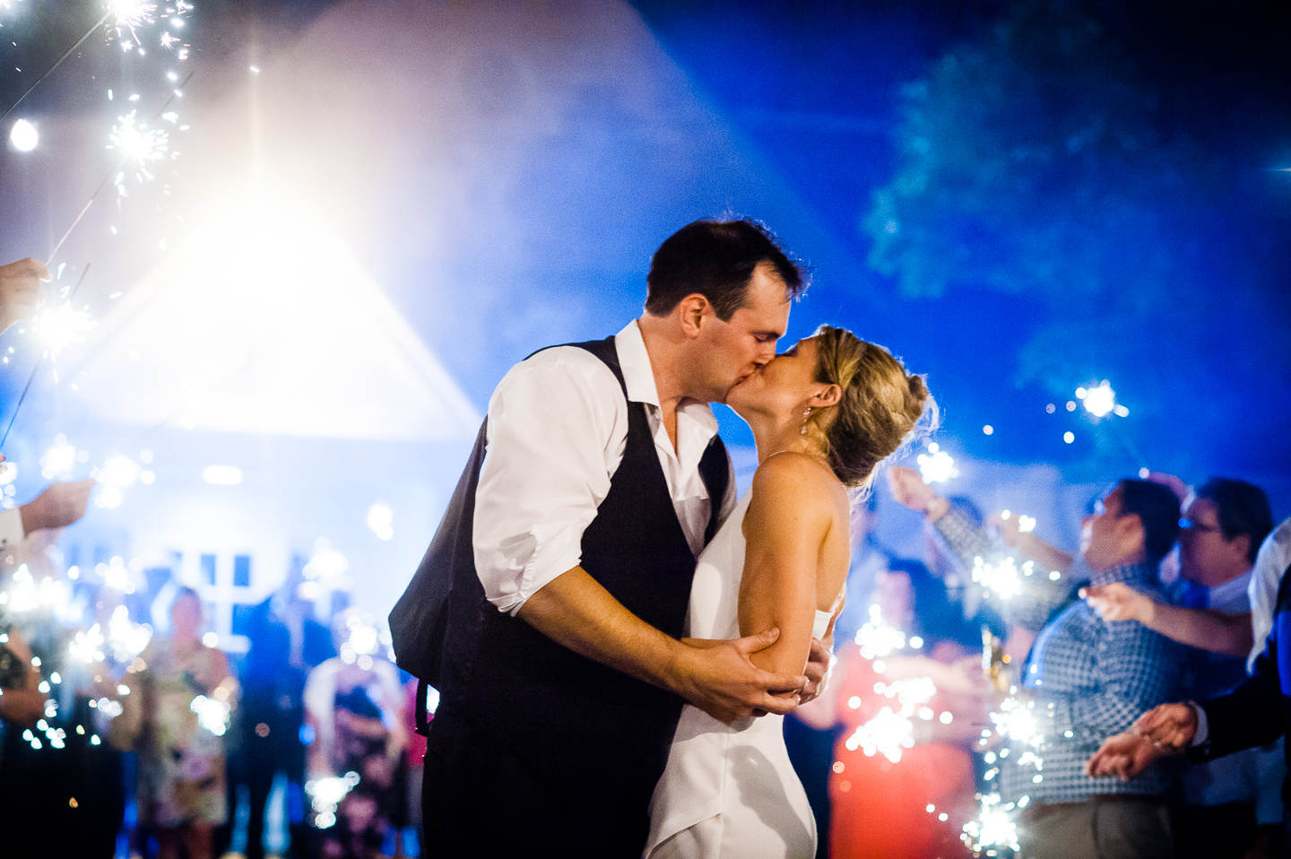 a bride and groom stop to kiss during their sparkler exit at the end of the wedding reception 