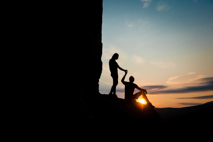 Mountaintop sunrise silhouette of recently engaged couple