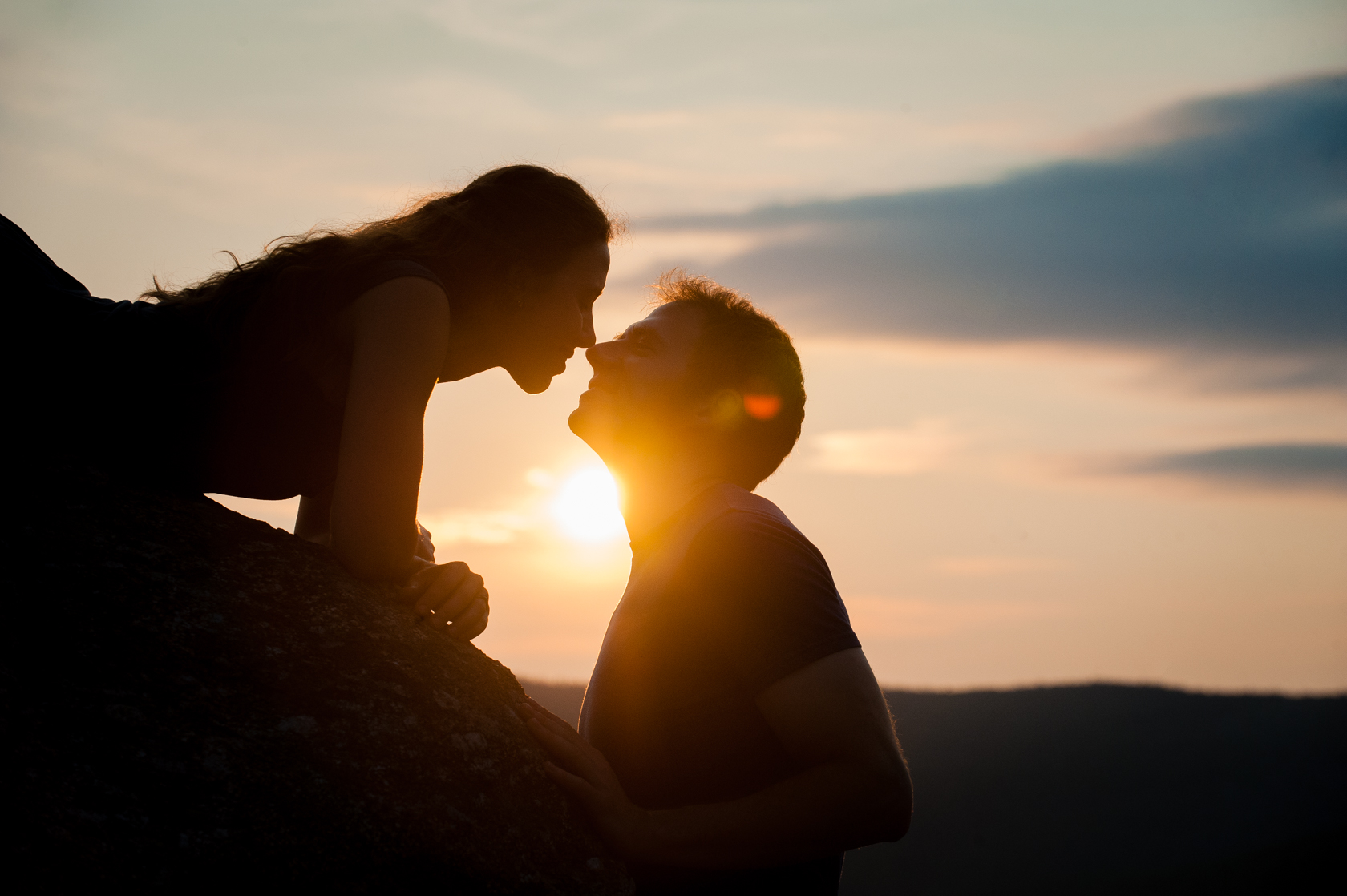 beautiful adventurous couple kiss at sunrise on a mountain