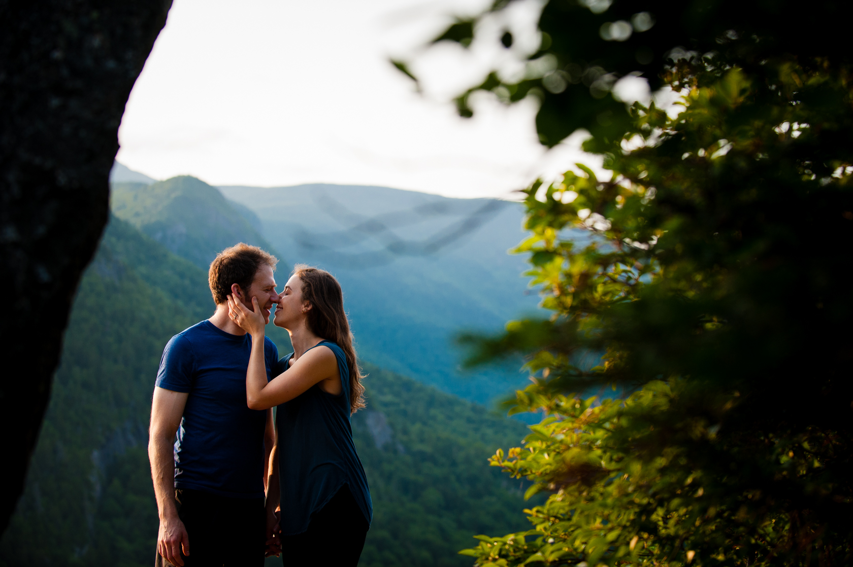 engaged couple kiss with gorgeous mountains behind them