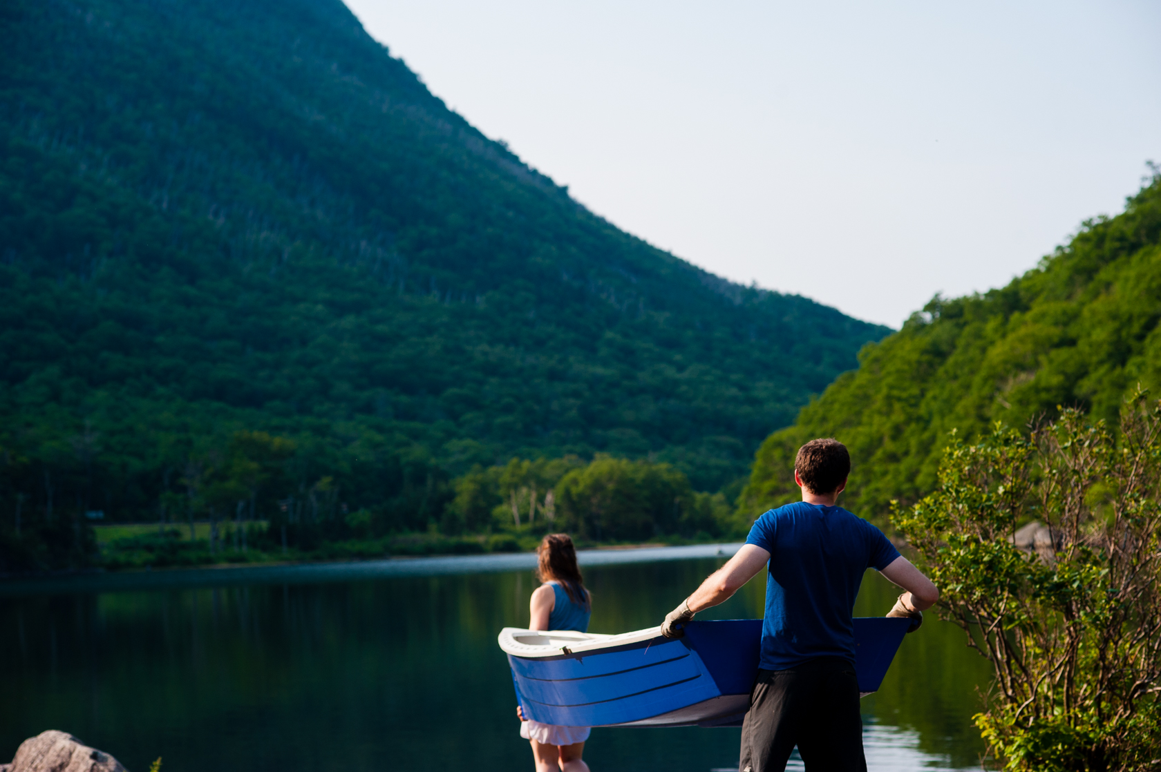 young couple carries boat to a beautiful mountain lake 