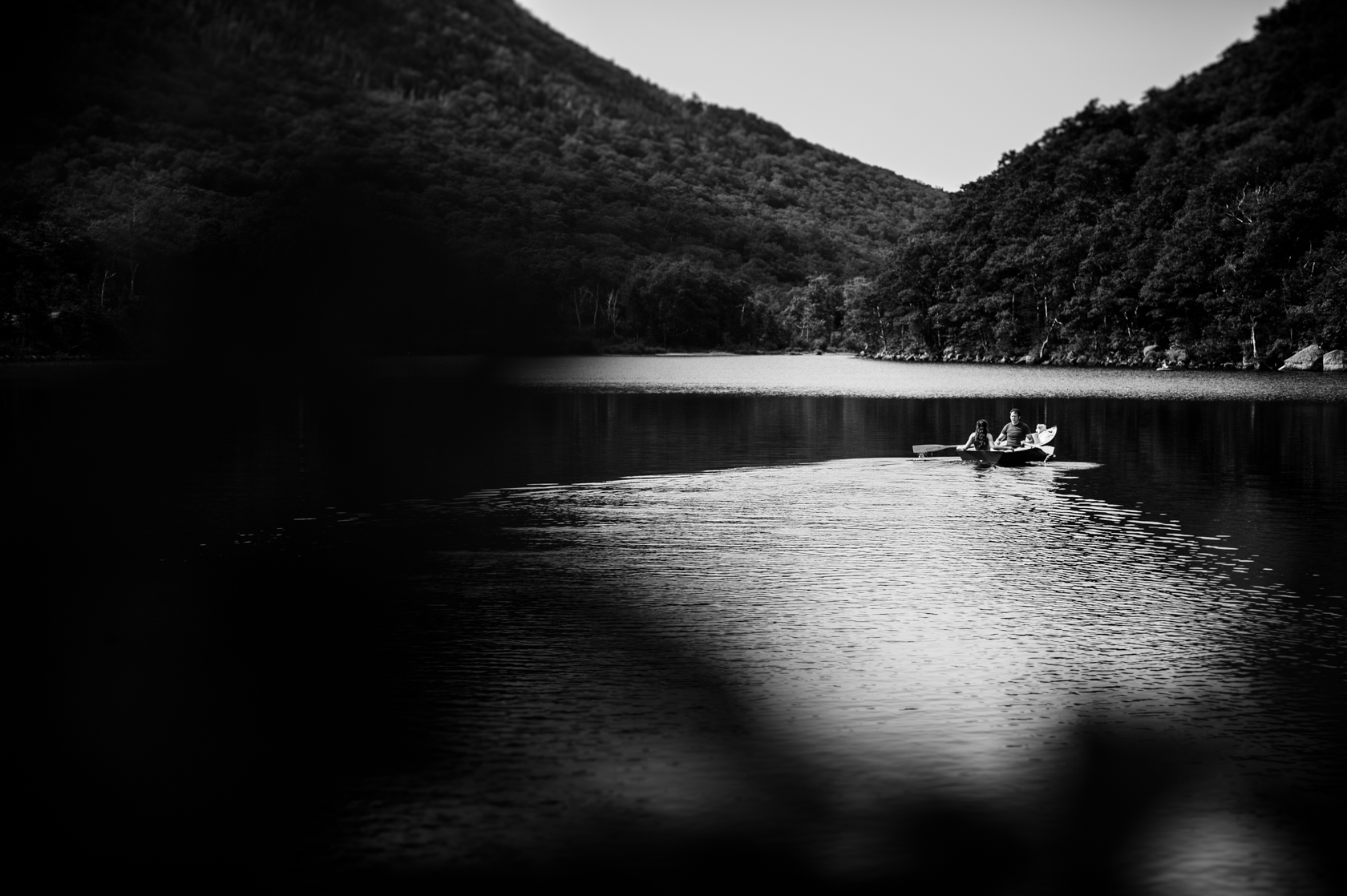 adorable engaged couple paddles their boat on a mountain lake 