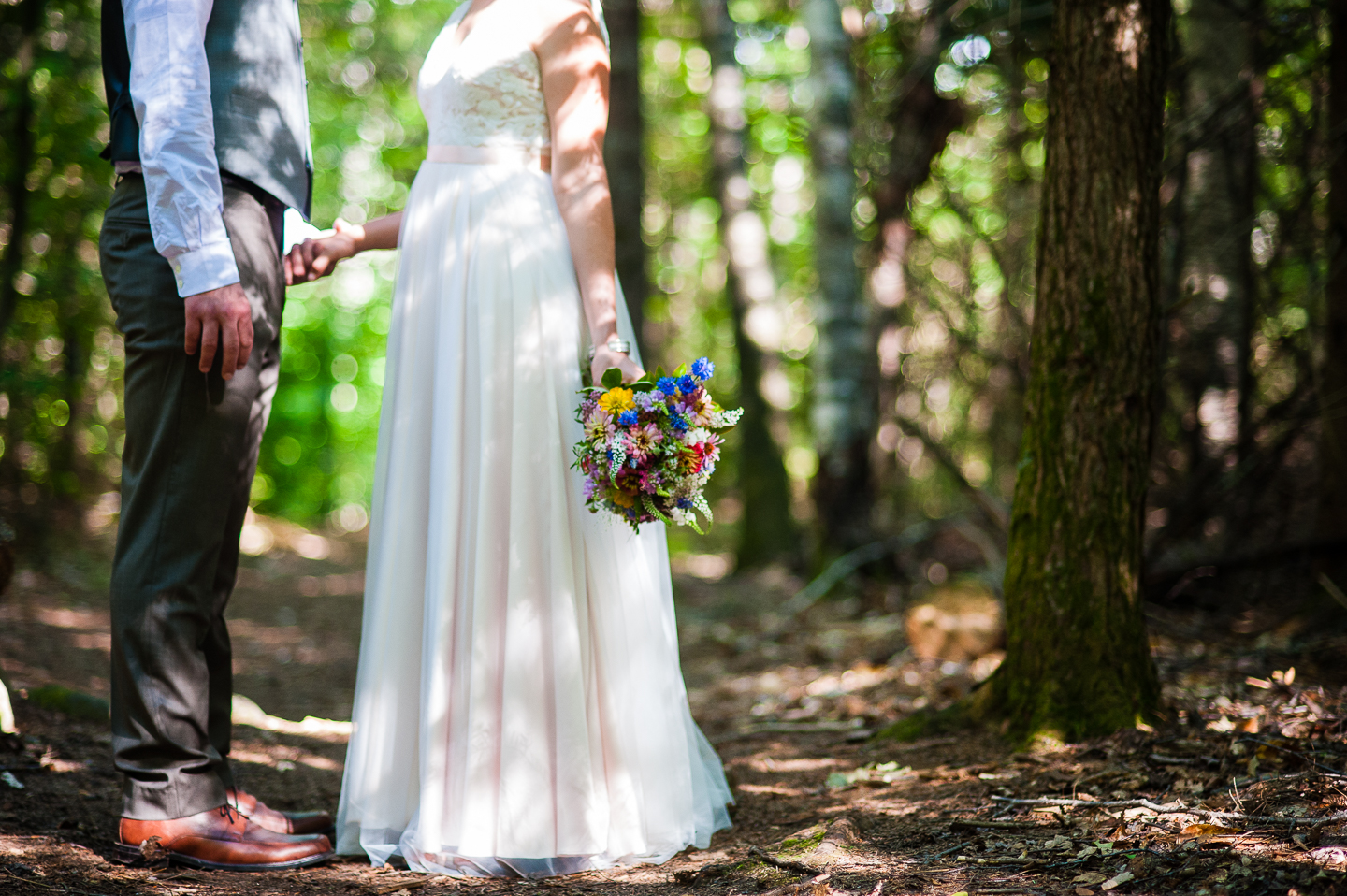 bride and groom hold hands in the middle of the woods 