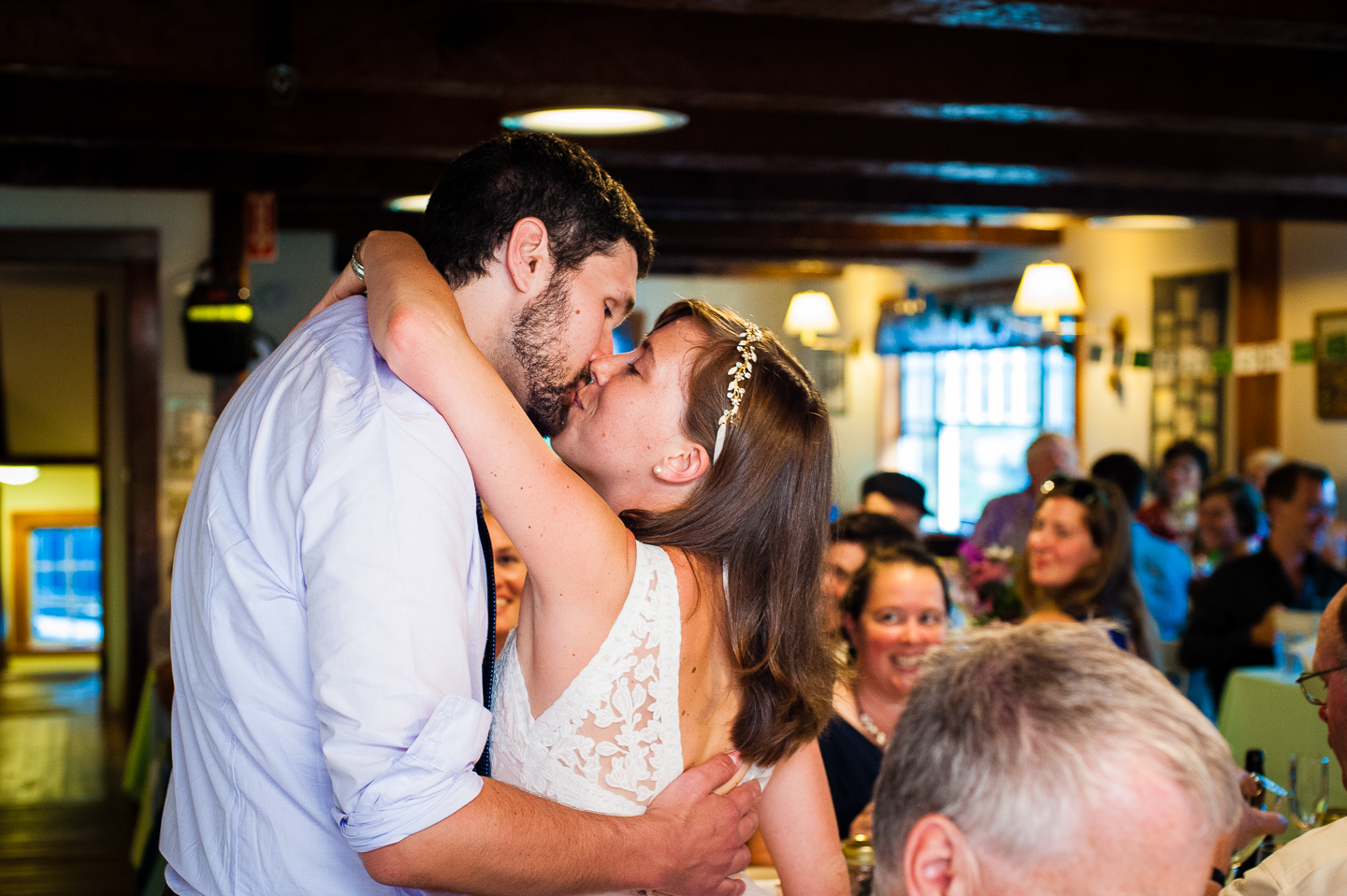 bride and groom kiss at the request of guests during their lodge style mountain wedding reception