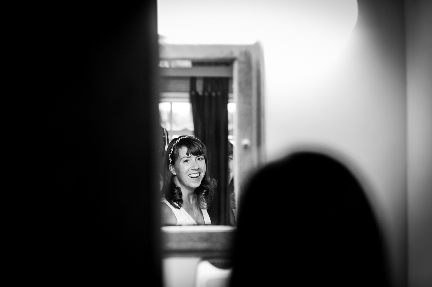 beautiful bride smiling into the mirror just before she heads to her woodsy wedding ceremony