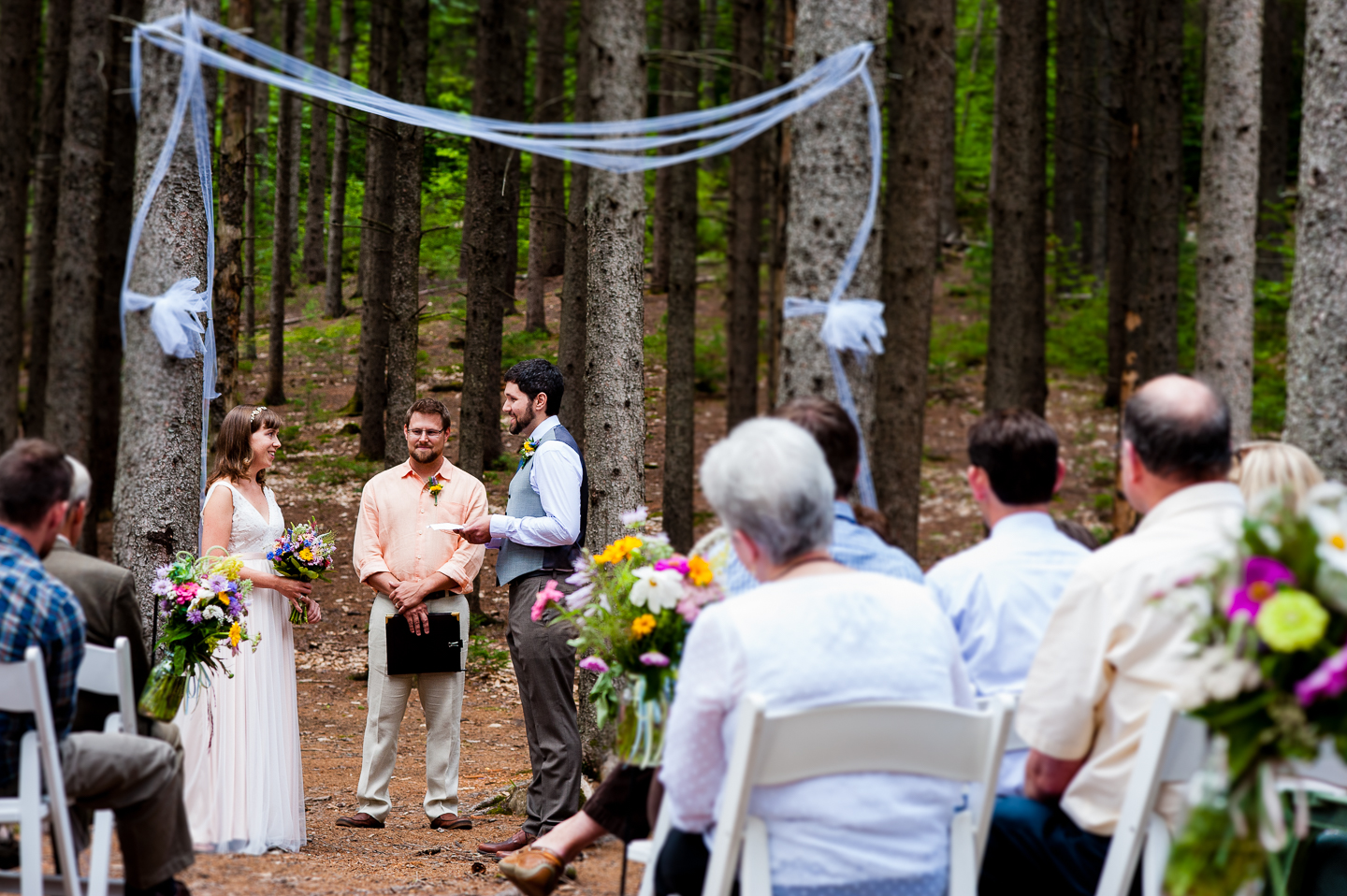 The bride and groom saying their vows during their gorgeous ceremony in the middle of the woods