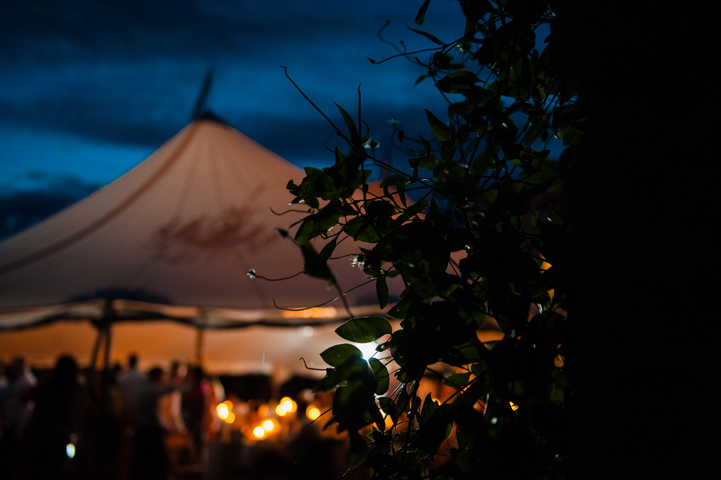 beautiful sailcloth tent lights up at night with bright blue sky behind