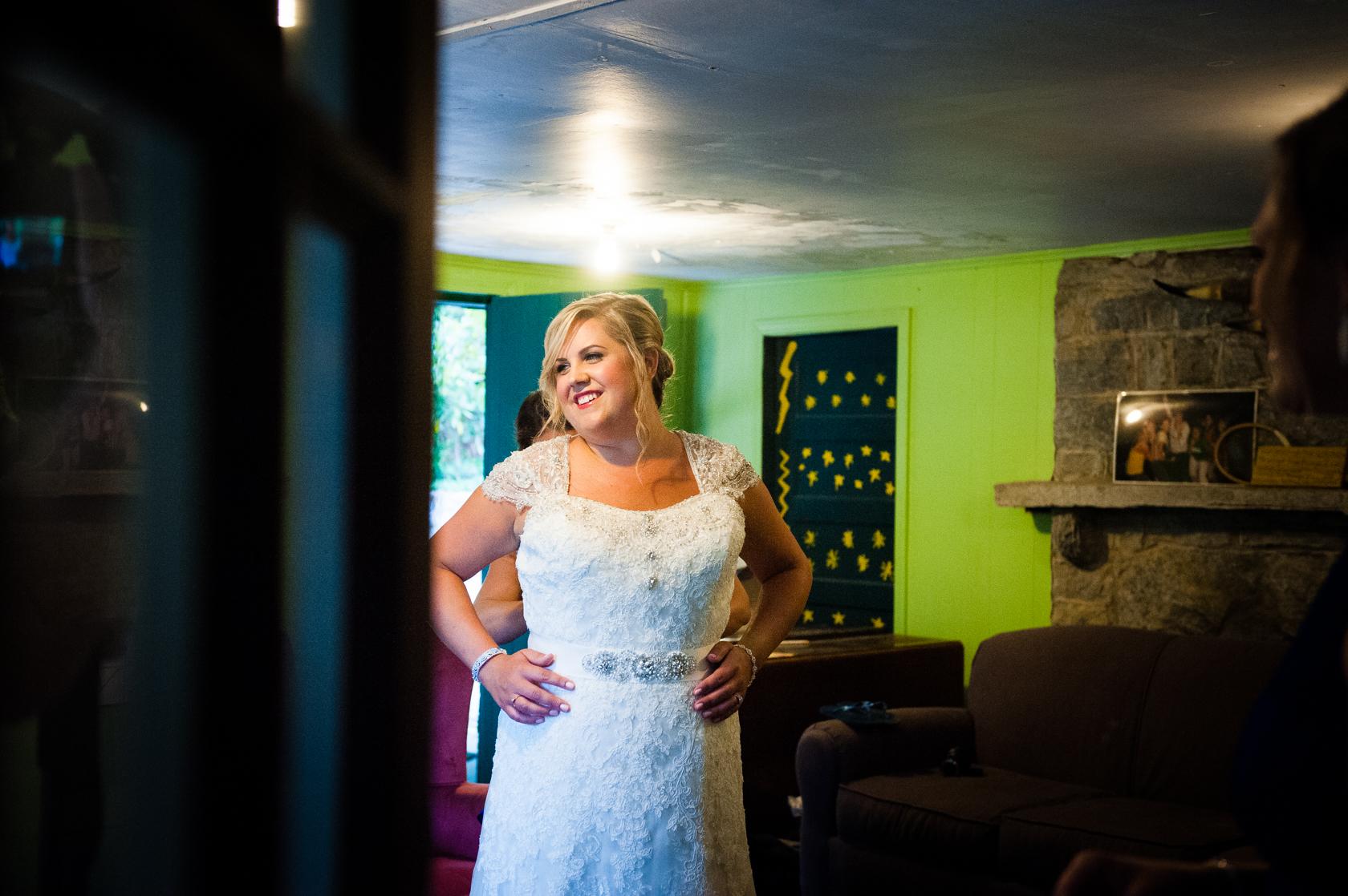 Gorgeous brides gets into her lace dress in the bunk house of a summer camp cabin