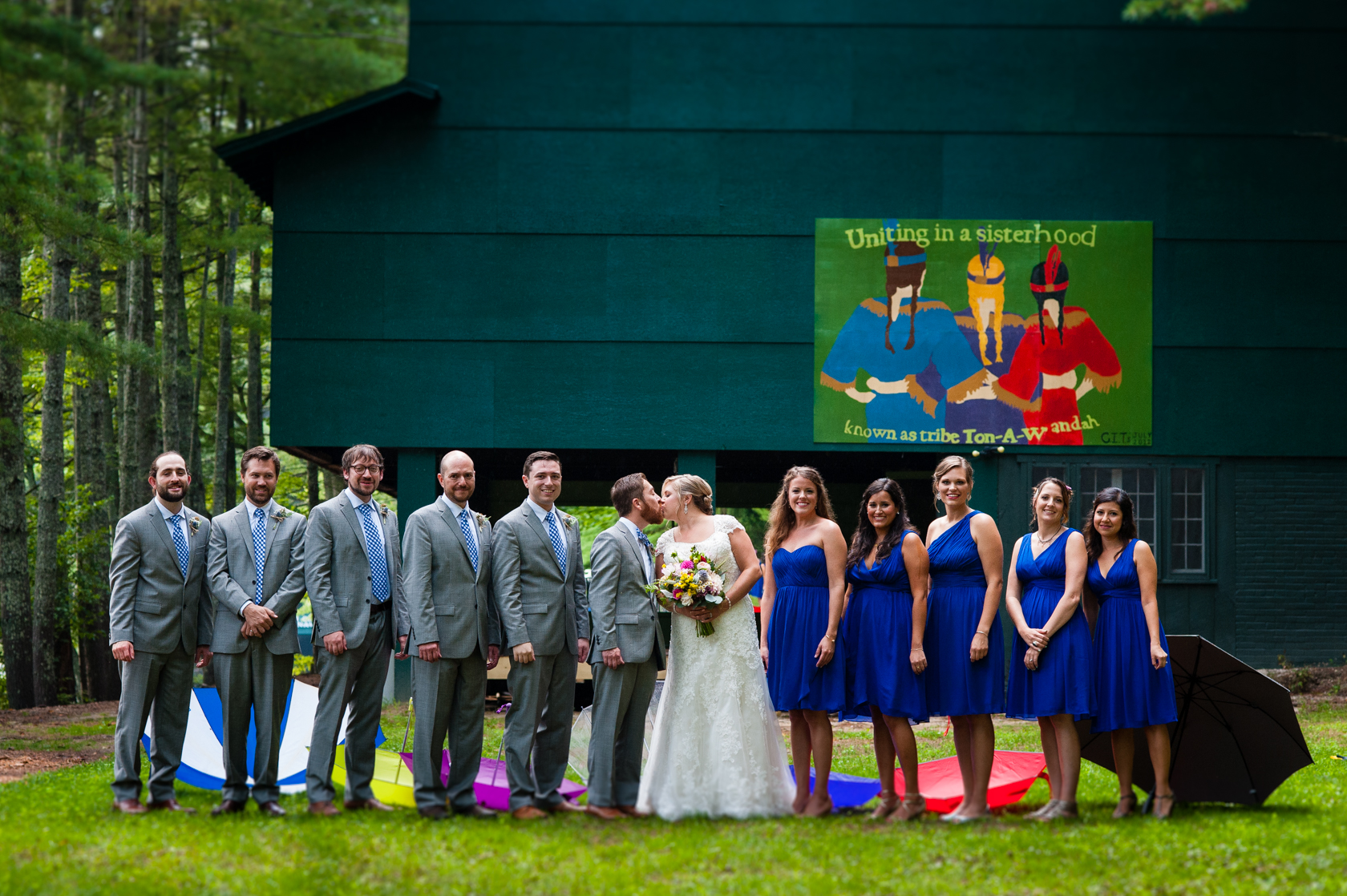 bride and groom with their wedding party stand together in front of Camp Ton a Wandah's bunk house 