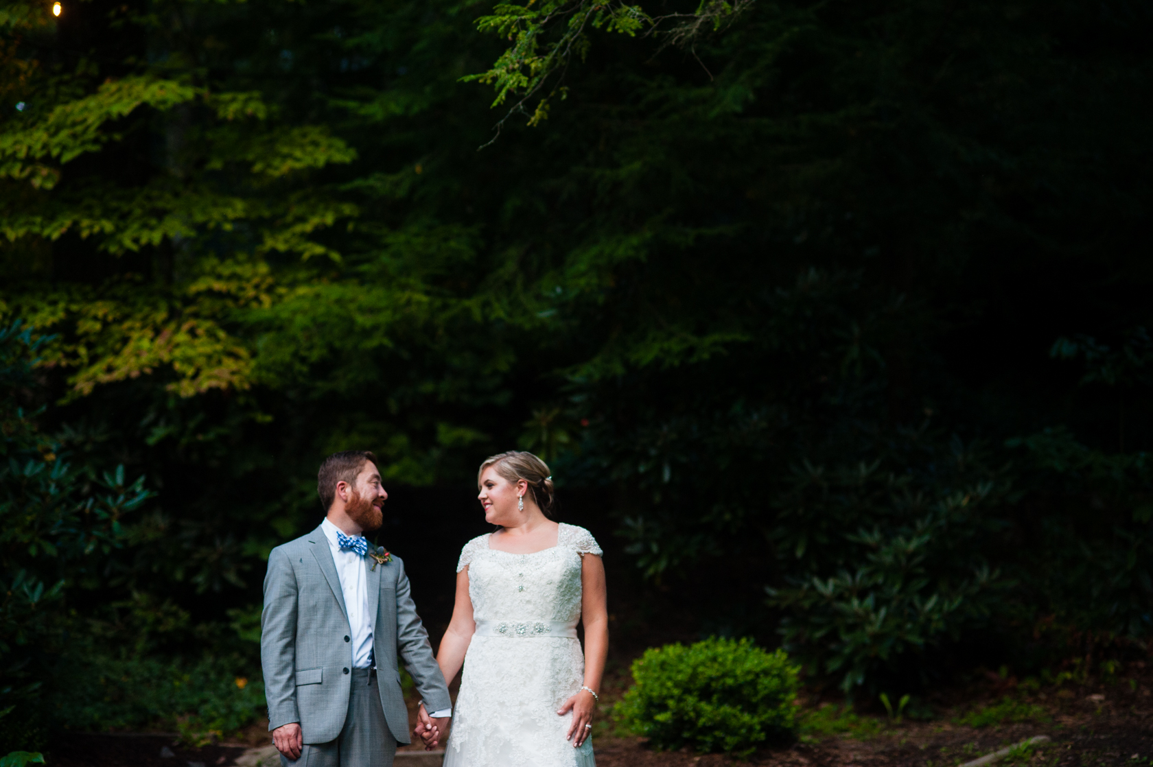 bride and groom hold hands during their portraits in the woods