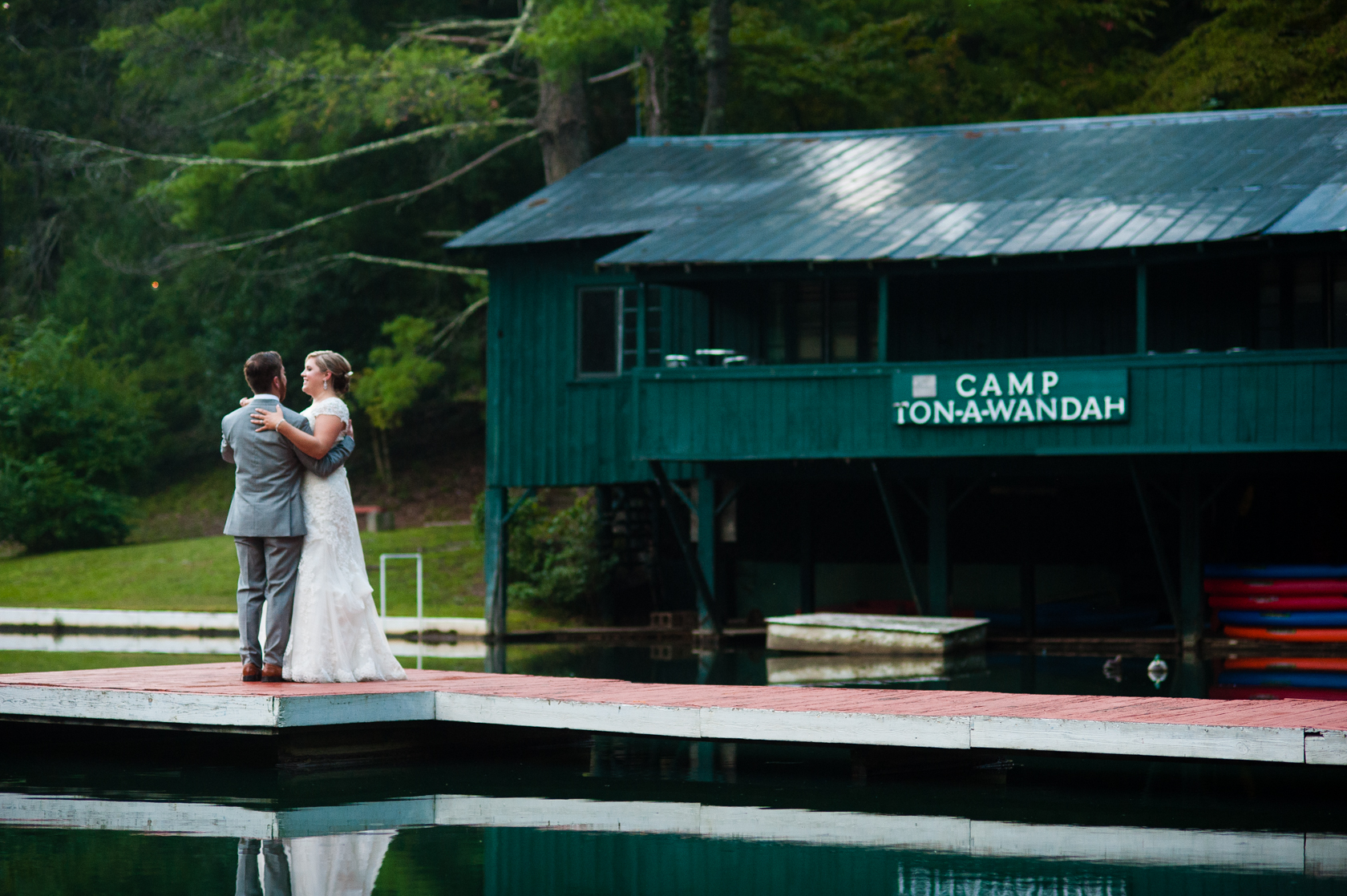 husband and wife practice their first dance on the boat dock at camp ton a wandah