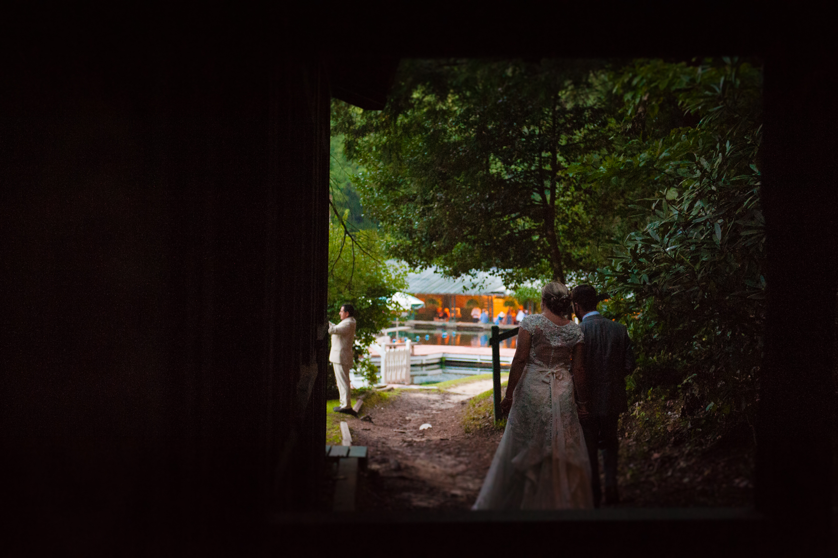 bride and groom walking down wooded path 