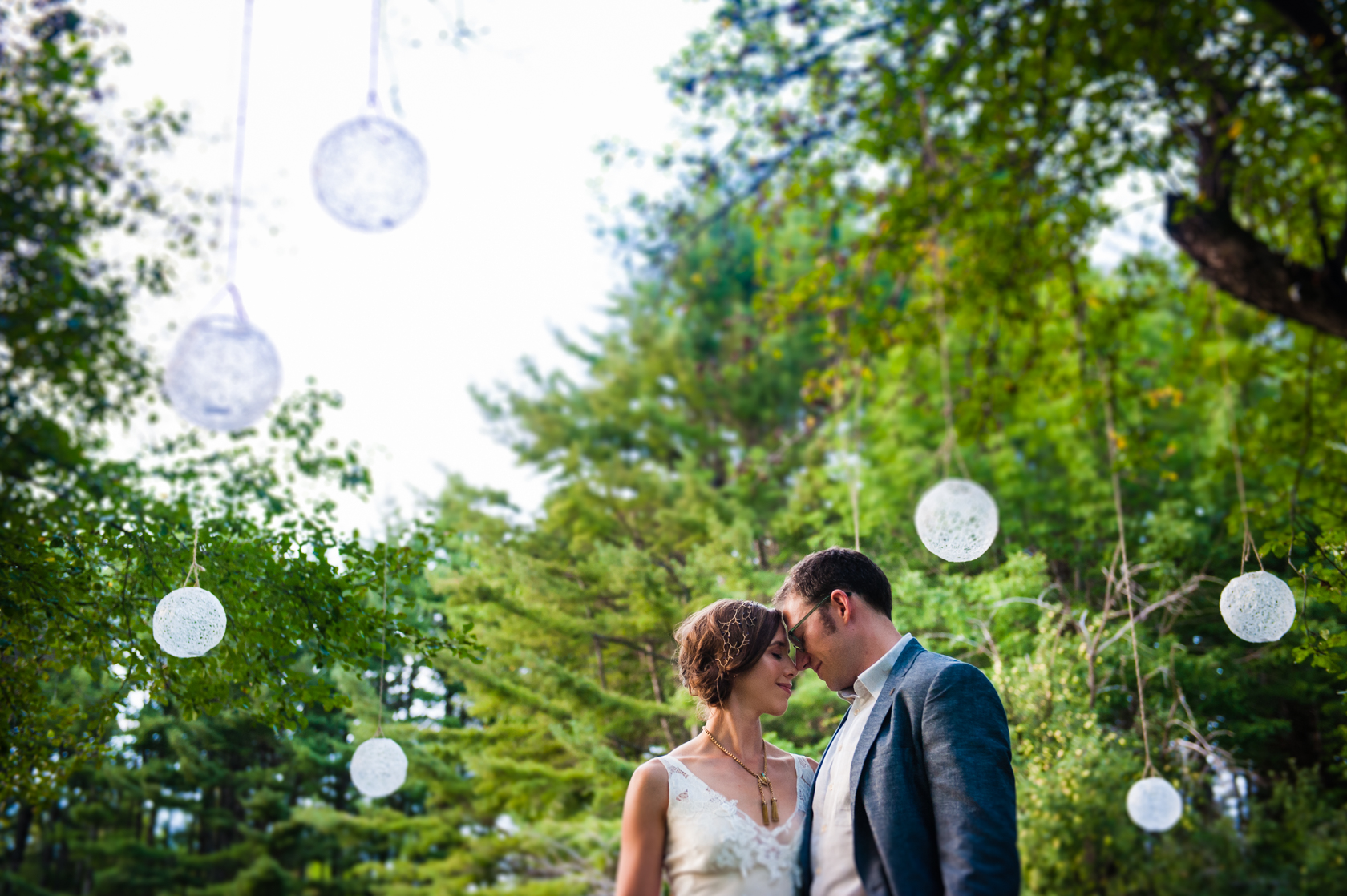 Beautiful couple embrace under diy hanging globes in a forest