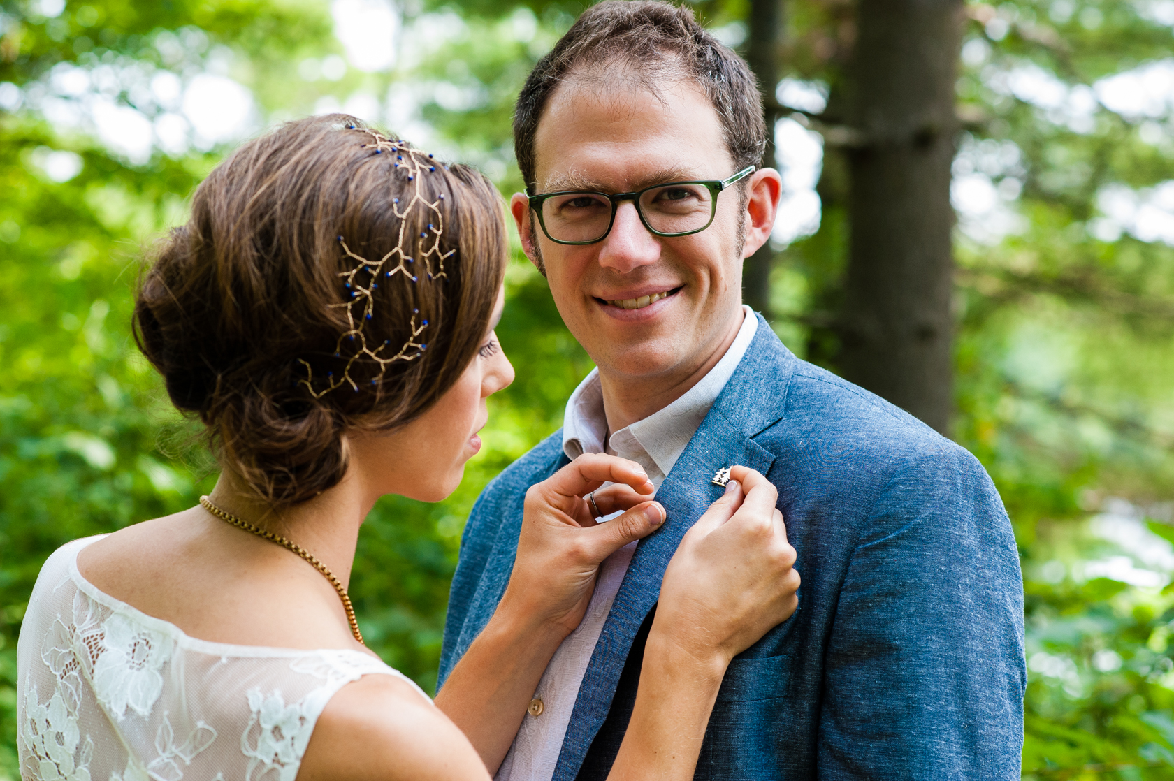 bride pins a lapel she made on her handsome groom