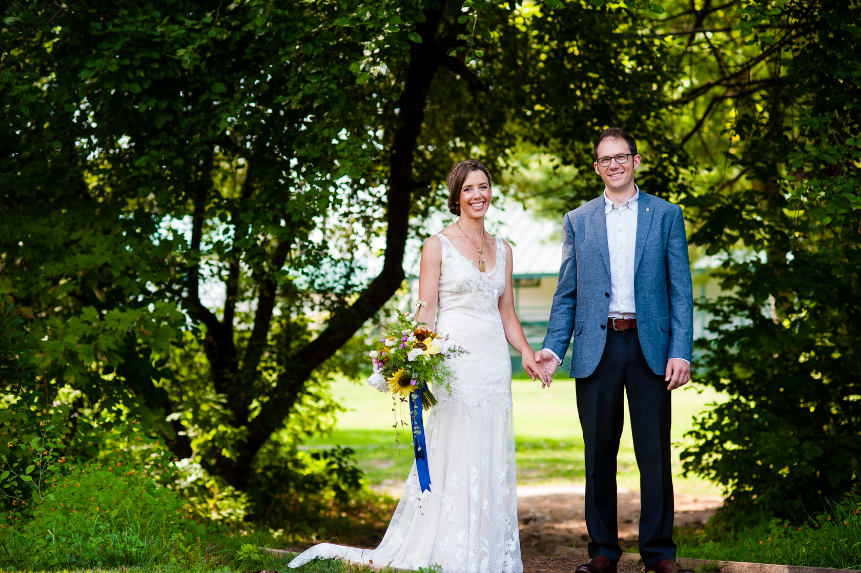 happy bride and groom holding hands in front of beautiful apple trees