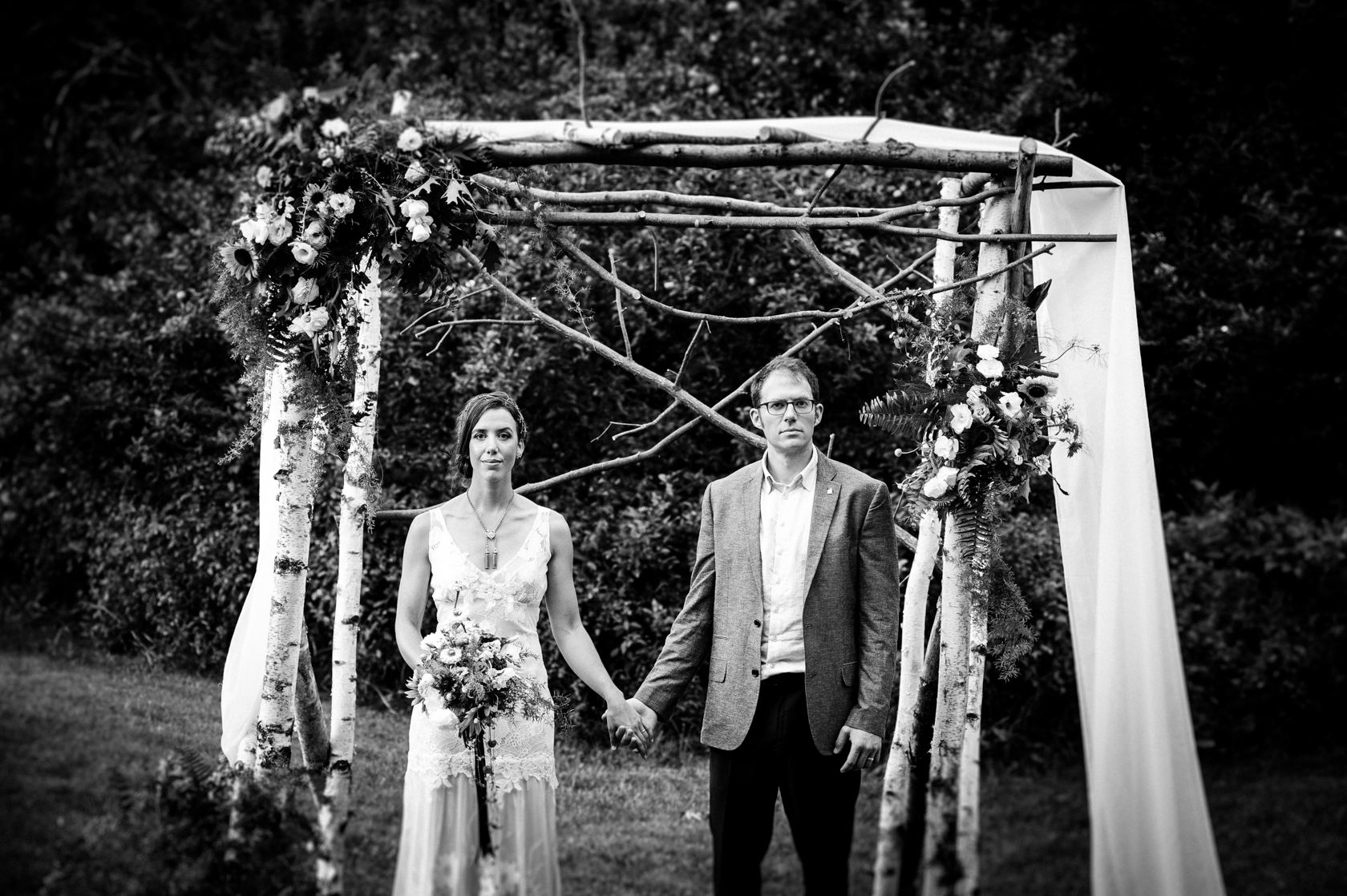 bride and groom hold hands in front their gorgeous handmade birch arbor