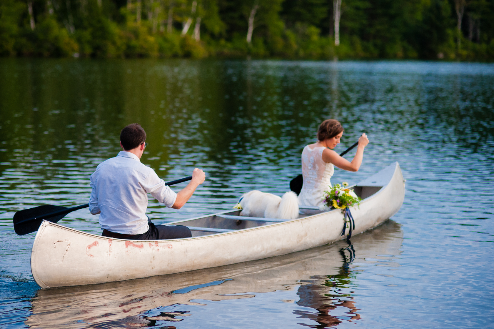 fun adventurous couple paddle a canoe on their wedding day with their dog