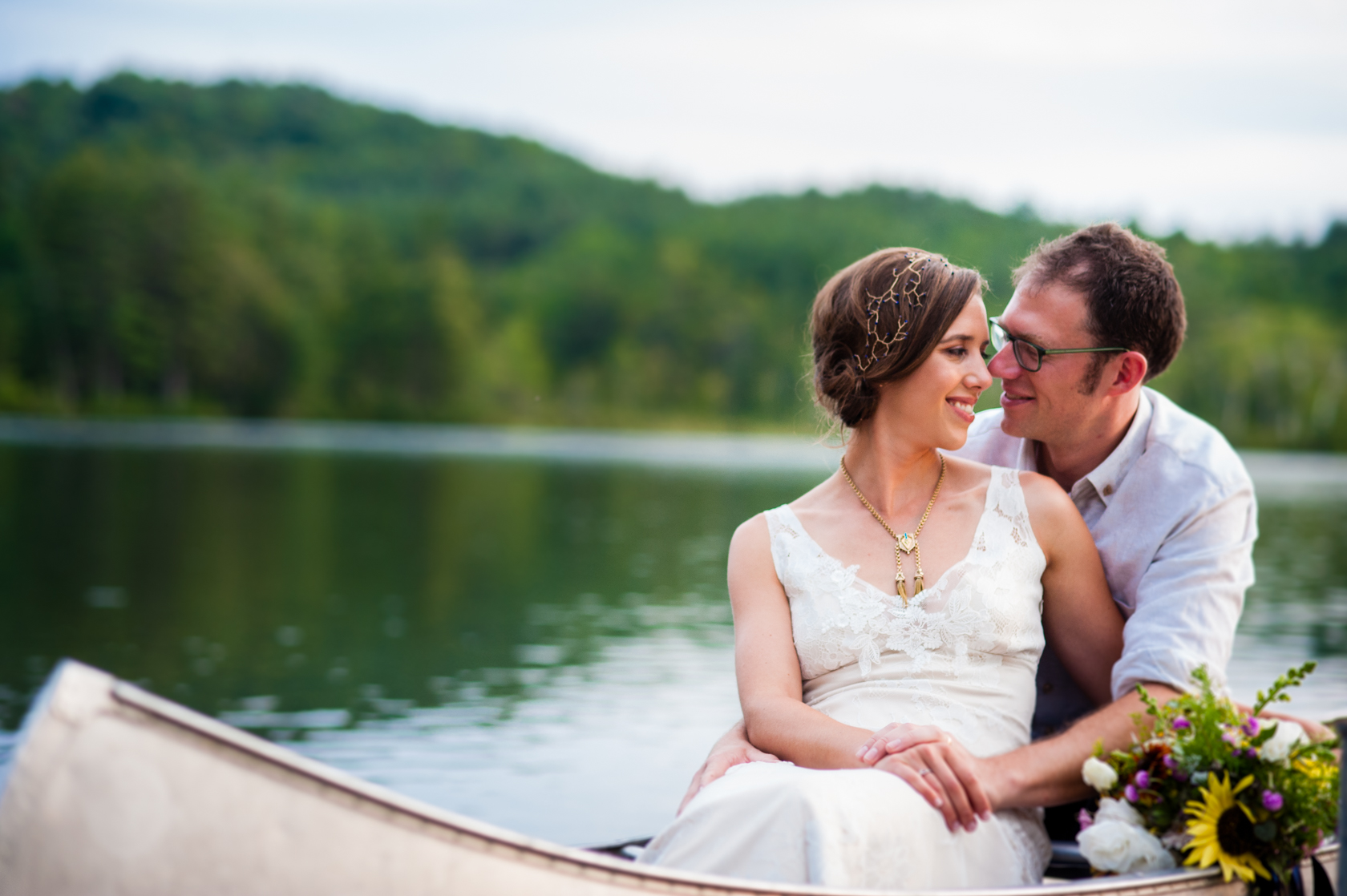 newly married couple snuggles up together in a canoe on their wedding day 