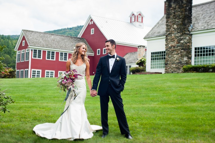 bride and groom holding hands in front of gorgeous red barn 