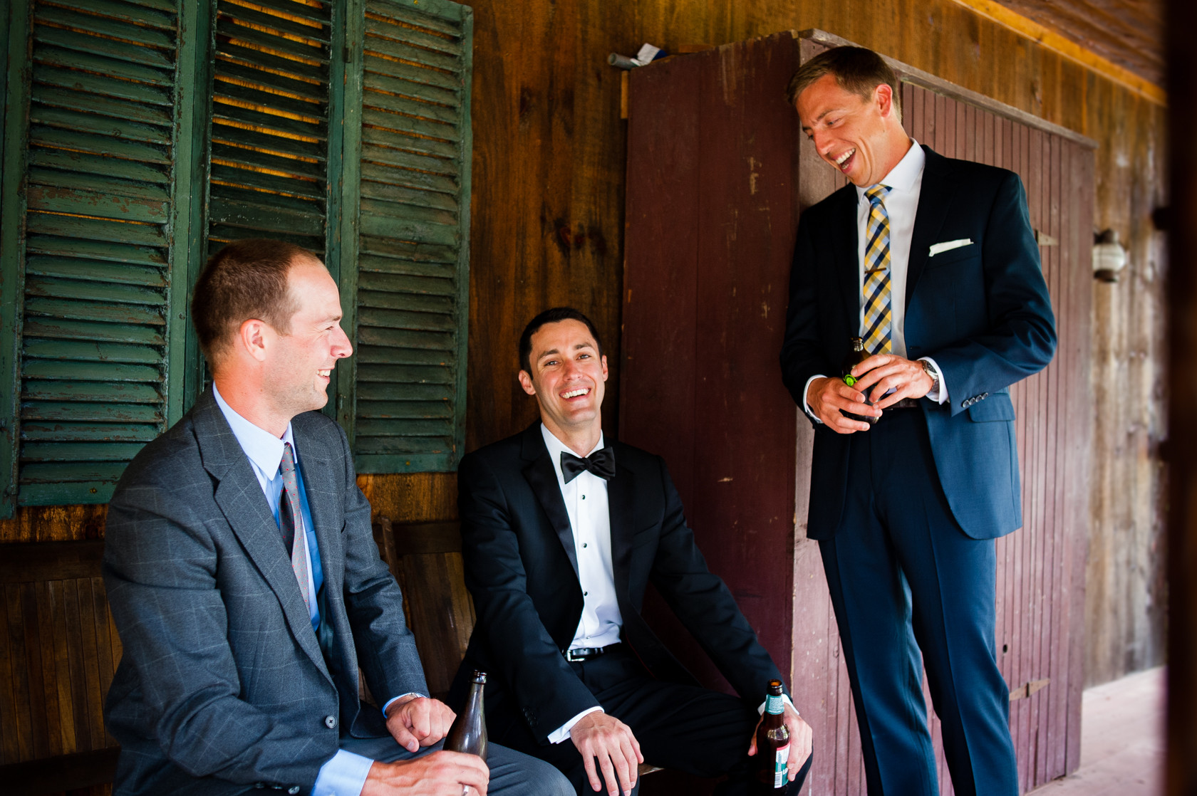 groom and his best men relax on their cabins front porch with a beer in hand 