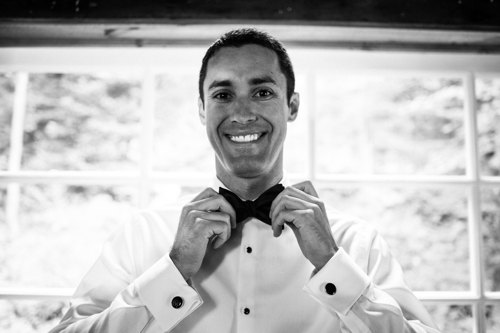 handsome groom fixes his bow tie 