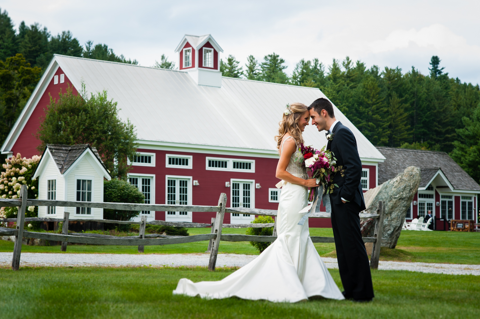 bride and groom forehead to forehead in front of red farm barn 