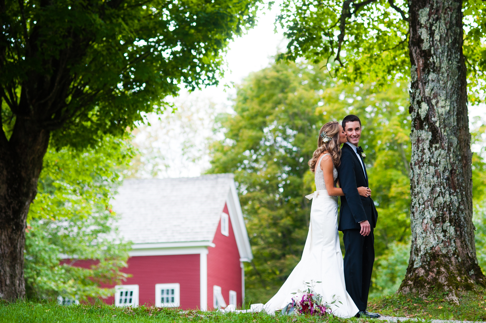 bride gives her new husband a kiss on the cheek during their gorgeous farm wedding 