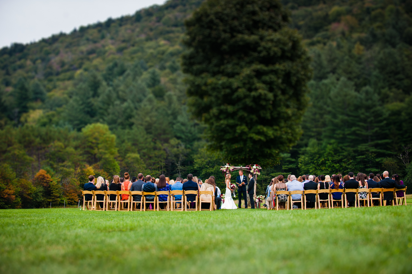 a wedding ceremony in a gorgeous field with vermonts green mountains  behind 