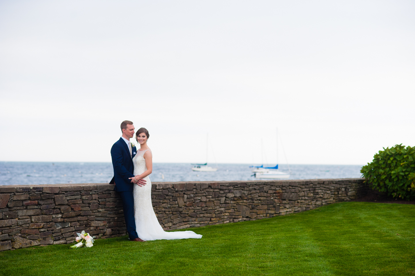 bride and groom stand on the wychmere beach club lawn with the gorgeous ocean behind