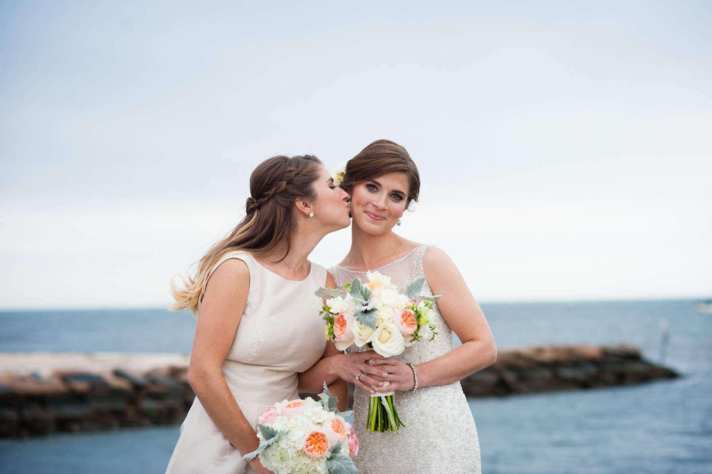 bridesmaid gives the beautiful bride a kiss on the cheek 